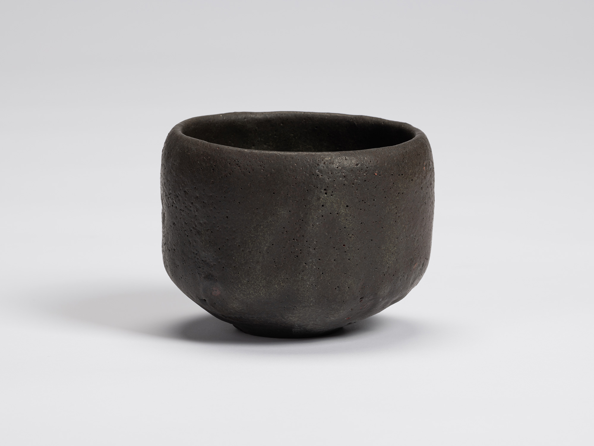 Front view of Chawan No. 12 by Shiro Tsujimura. The hand-formed black tea bowl features a gently...