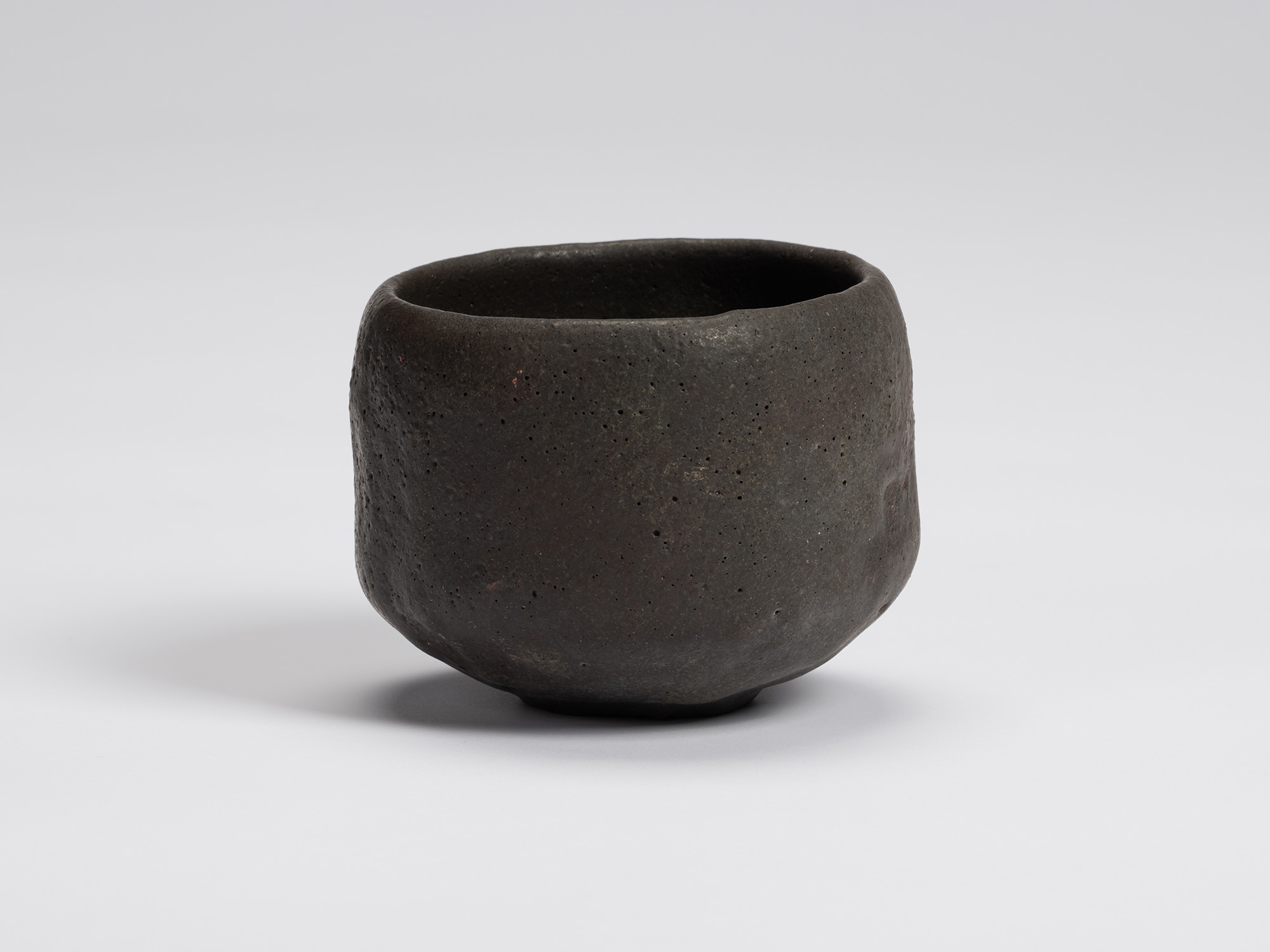 Front view of Chawan No. 12 by Shiro Tsujimura. The hand-formed black tea bowl features a gently...