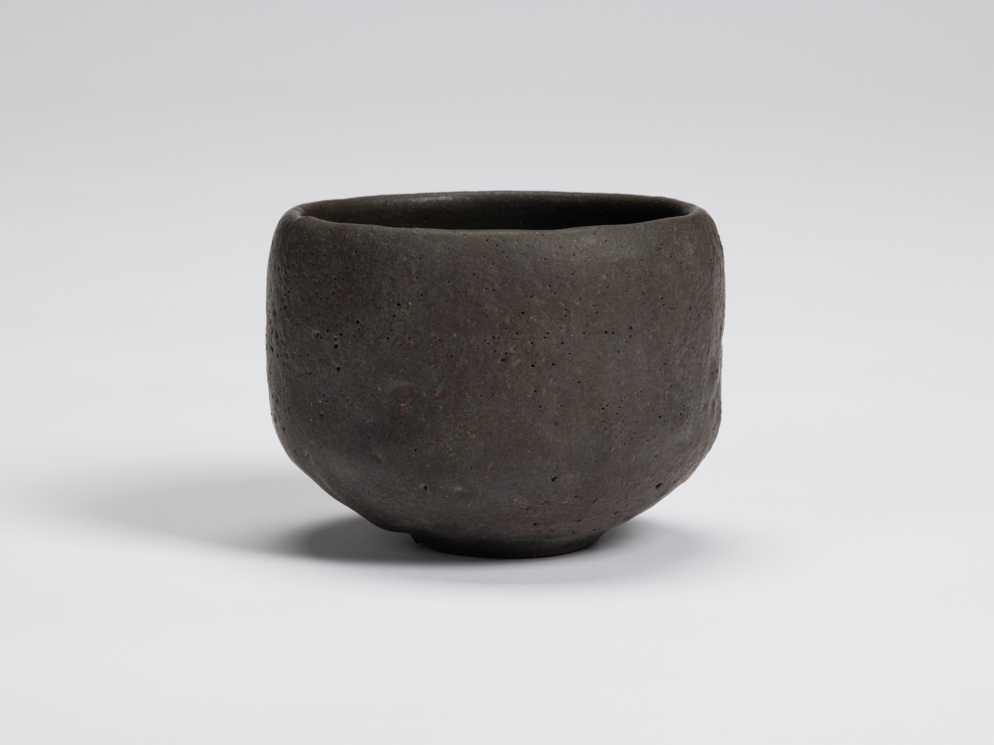 Front view of Chawan No. 12 by Shiro Tsujimura. The hand-formed black tea bowl features a gently...