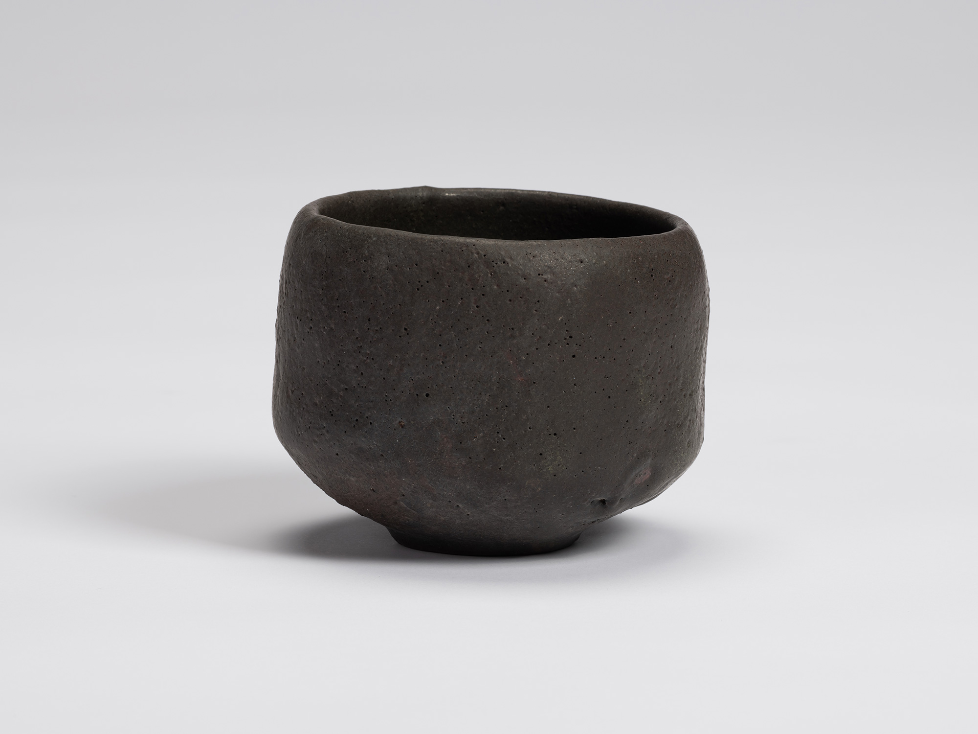 Front view of Chawan No. 12 by Shiro Tsujimura. The hand-formed black tea bowl features a gently...