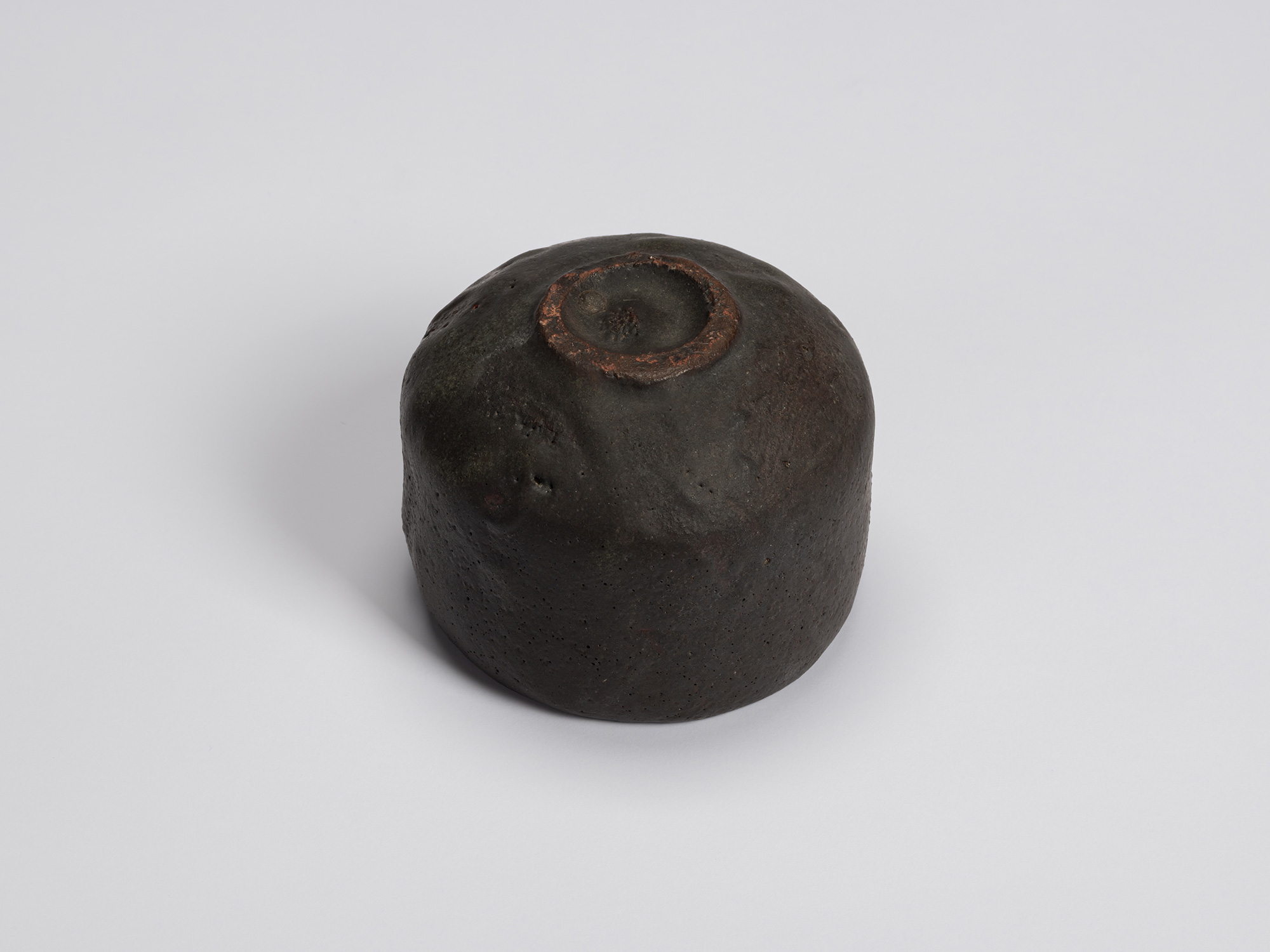 Underside of Chawan No. 12 revealing a small circular foot ring with exposed reddish clay around...