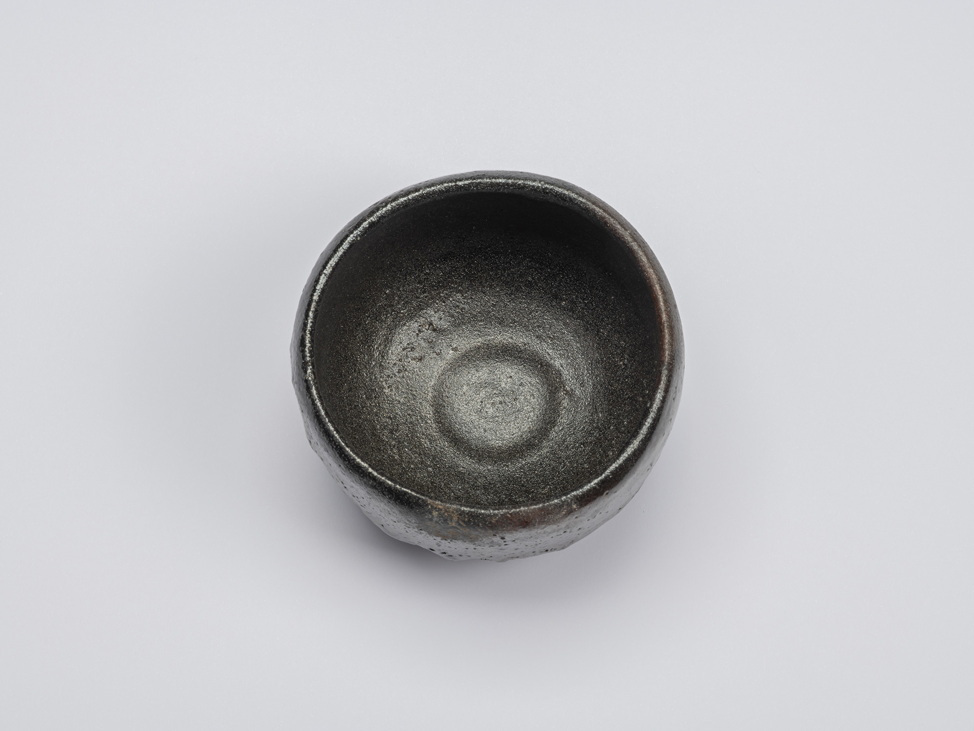 Overhead view of Chawan No. 13 showing the bowl's gently rounded interior. A lustrous charcoal-black...