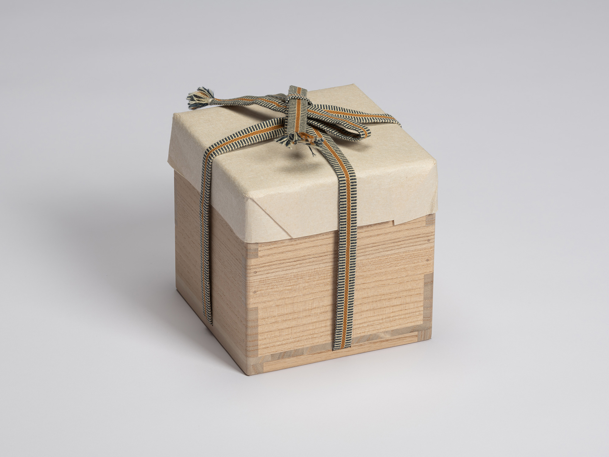 Wooden tomobako for Chawan No. 13, wrapped in protective paper and secured with a striped blue,...