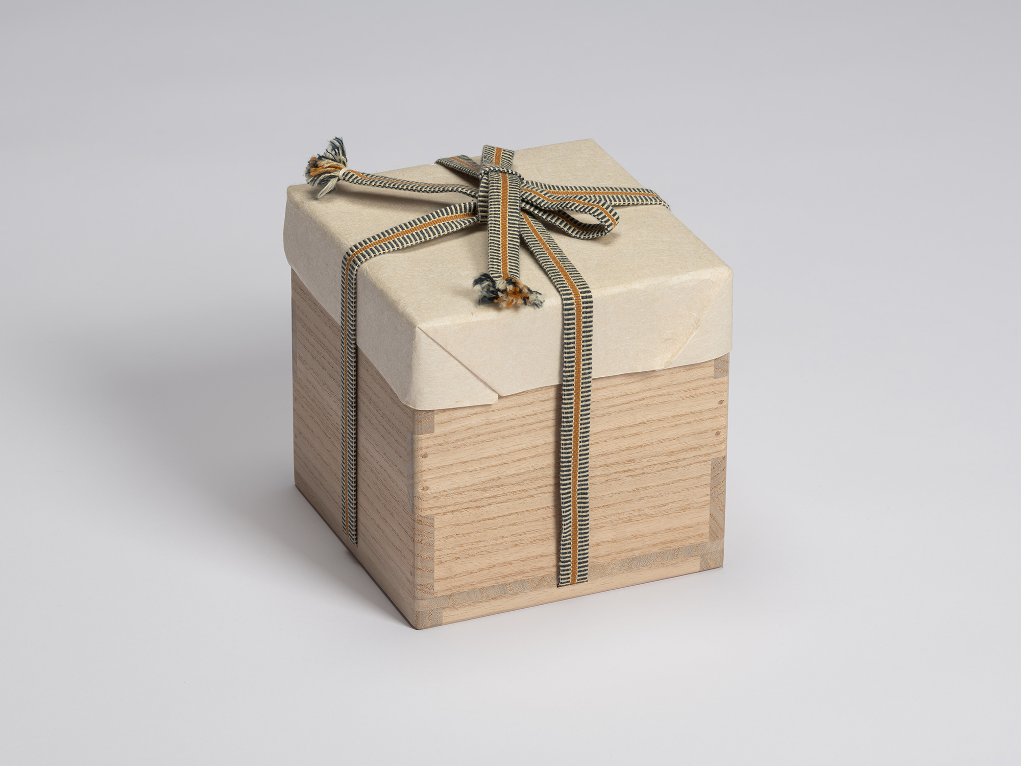 Closed paulownia wood tomobako for Chawan No. 14 by Shiro Tsujimura, wrapped in cream-colored protective...