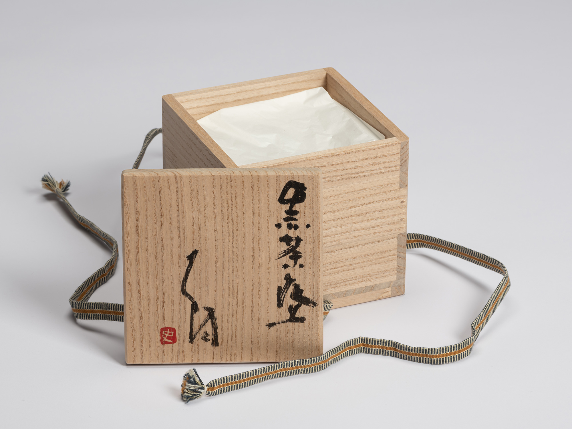 Open paulownia wood tomobako for Chawan No. 15 with the lid placed in front of the box. The lid...