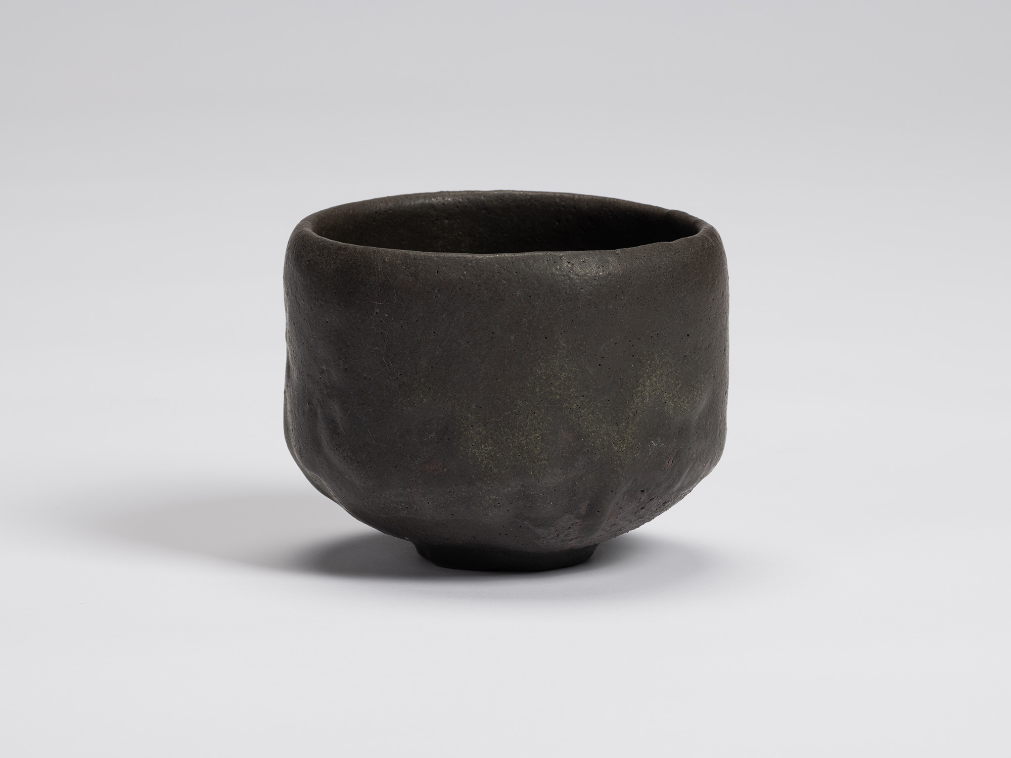 Front view of Chawan No. 16 by Shiro Tsujimura, a hand-formed black tea bowl with gently faceted...