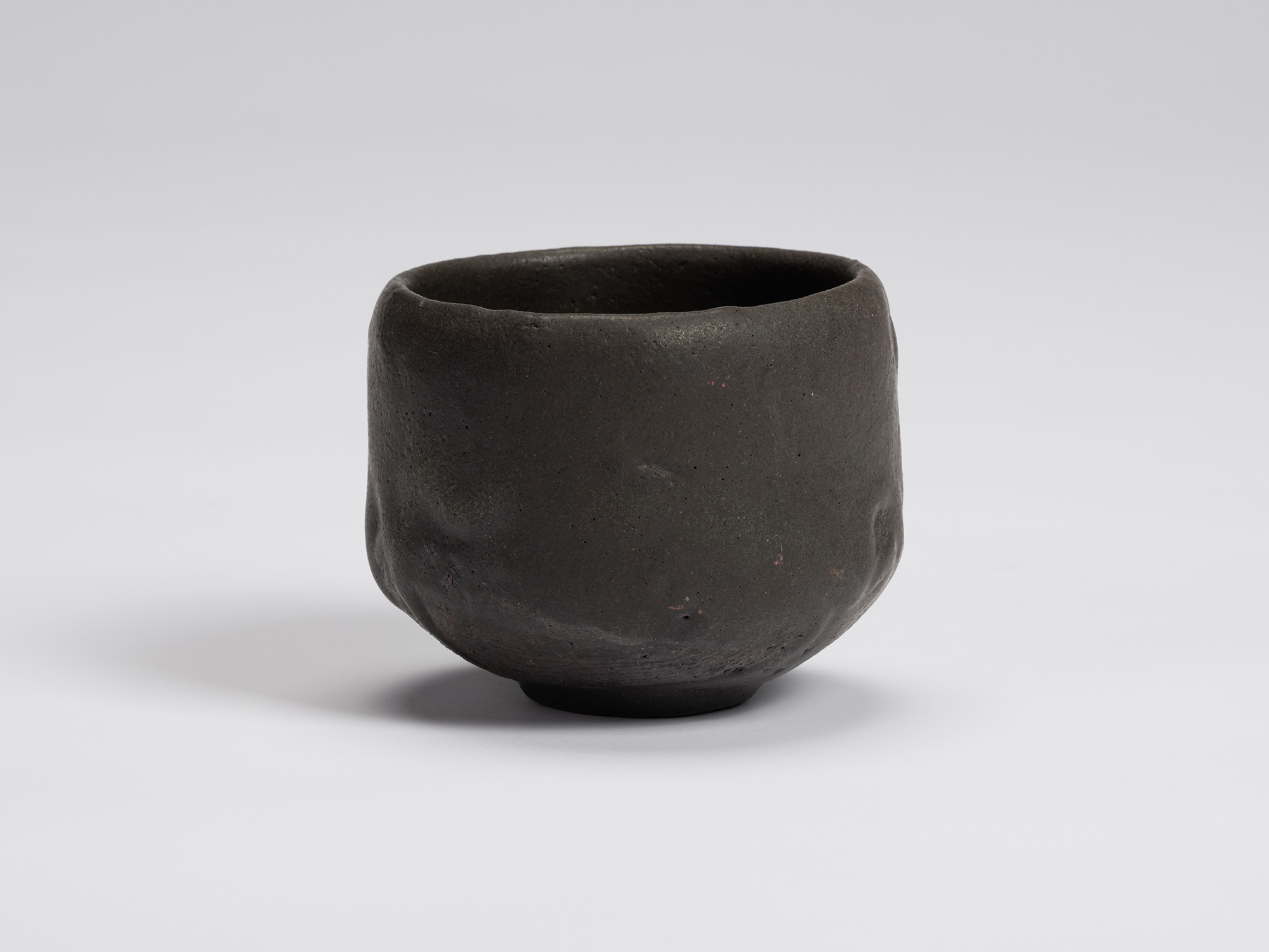 Front view of Chawan No. 16 by Shiro Tsujimura, a hand-formed black tea bowl with gently faceted...