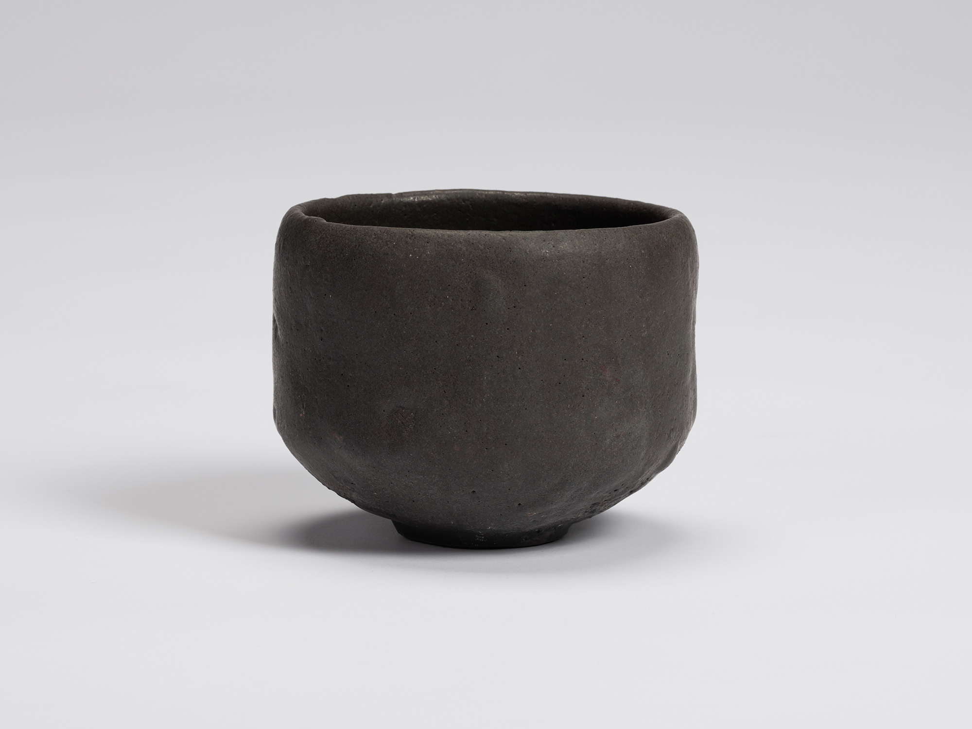 Front view of Chawan No. 16 by Shiro Tsujimura, a hand-formed black tea bowl with gently faceted...