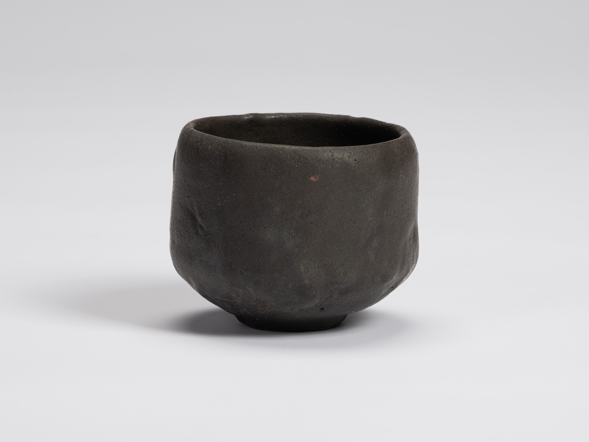 Front view of Chawan No. 16 by Shiro Tsujimura, a hand-formed black tea bowl with gently faceted...
