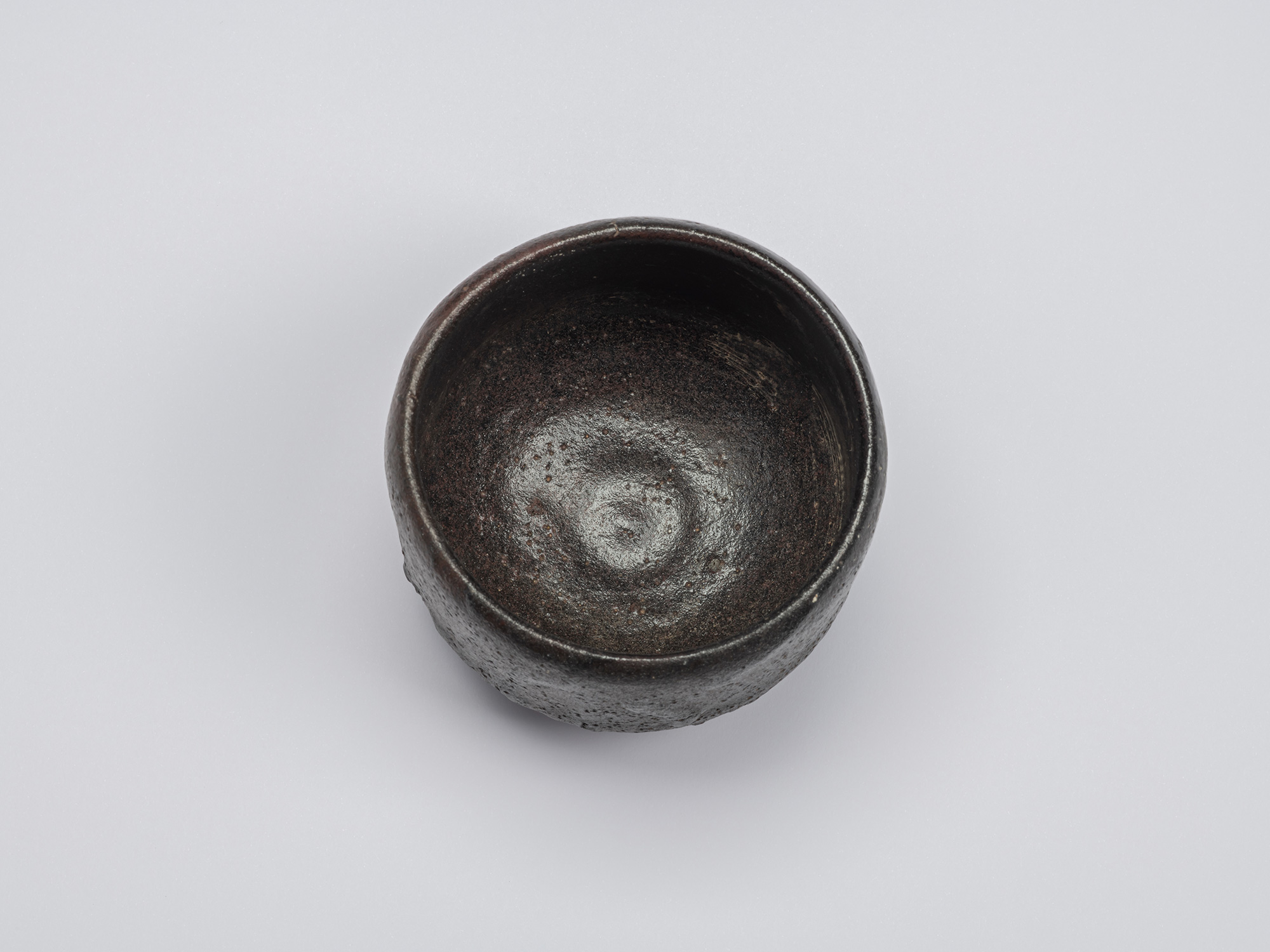 Overhead view of Chawan No. 17, revealing its circular opening, slightly uneven rim, and dark interior...