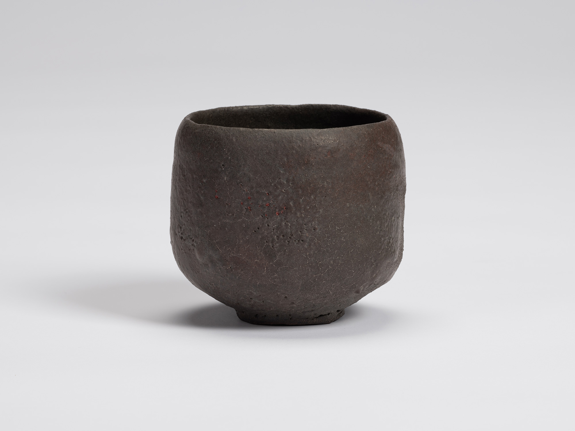 View of Kuro Chawan by Shiro Tsujimura, a hand-formed black tea bowl with gently rounded walls,...