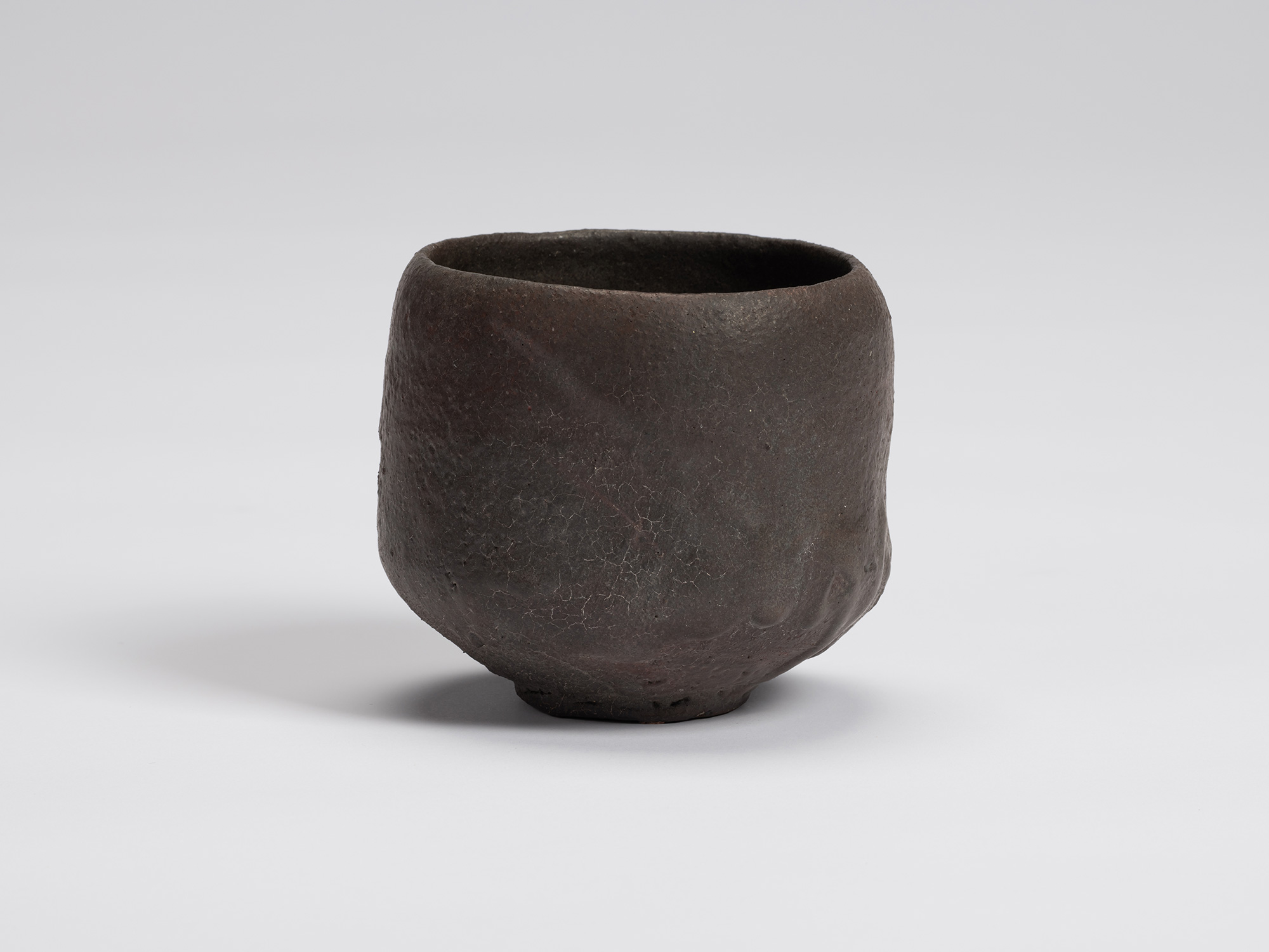 View of Kuro Chawan by Shiro Tsujimura, a hand-formed black tea bowl with gently rounded walls,...