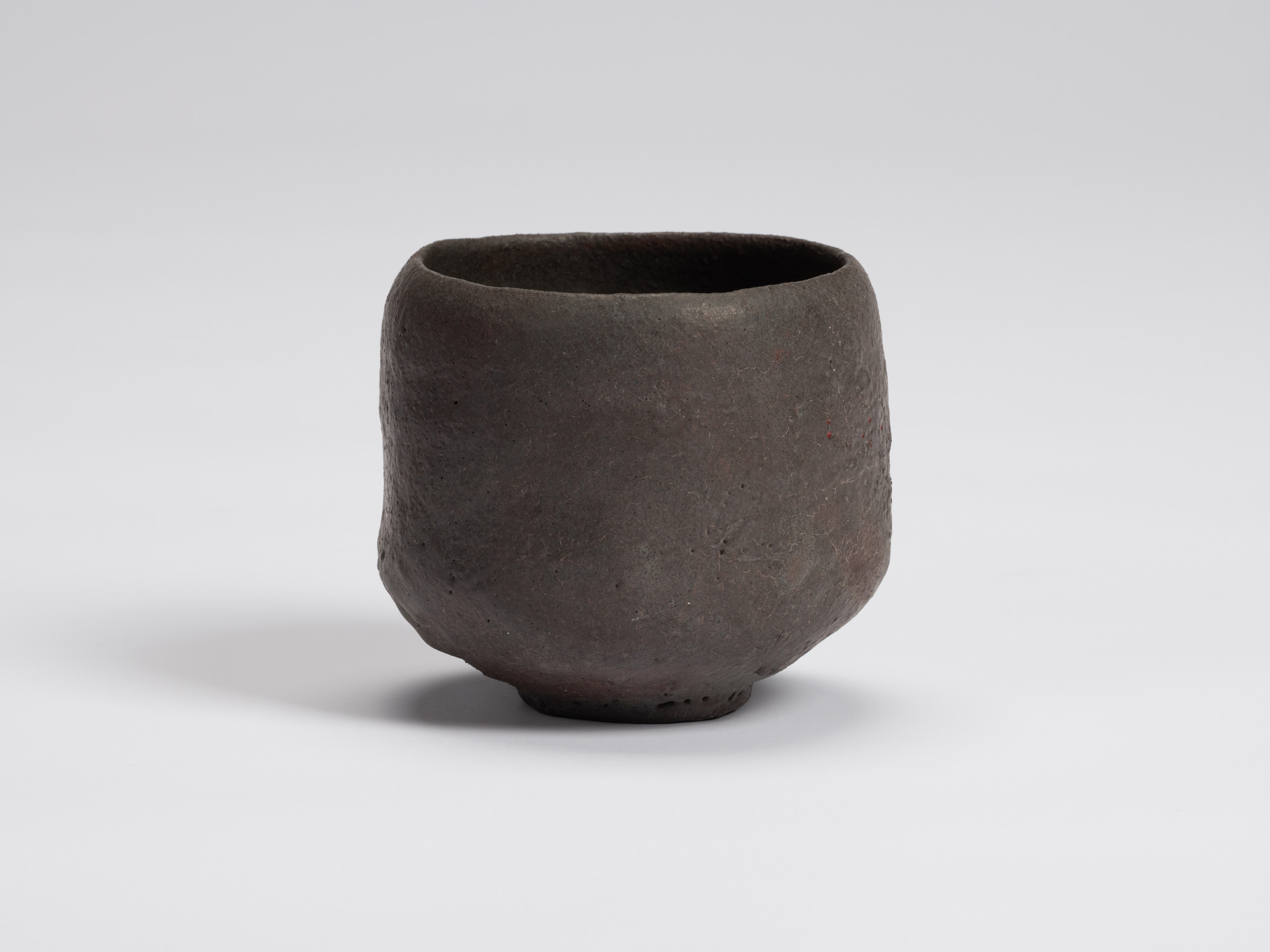 View of Kuro Chawan by Shiro Tsujimura, a hand-formed black tea bowl with gently rounded walls,...