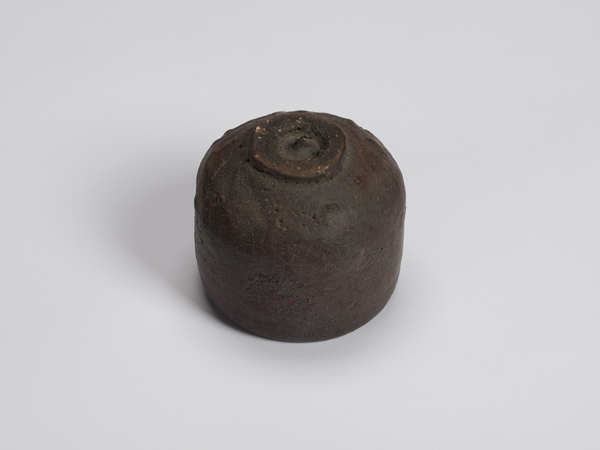 Bottom view of Kuro Chawan, showing its neatly trimmed circular foot ring surrounded by a dark,...