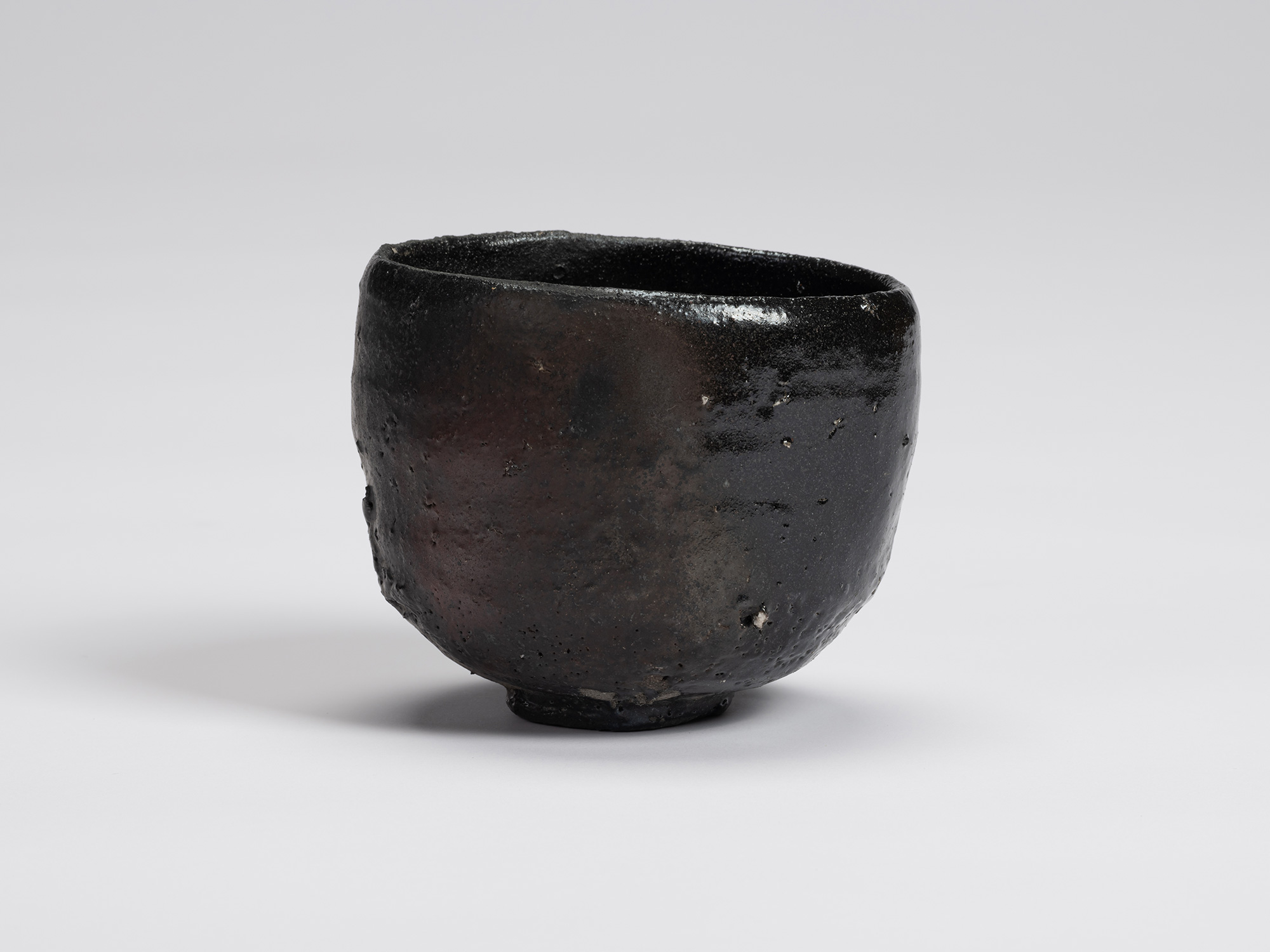 Front view of Kuro Chawan by Shiro Tsujimura, a hand-formed black tea bowl with softly rounded...