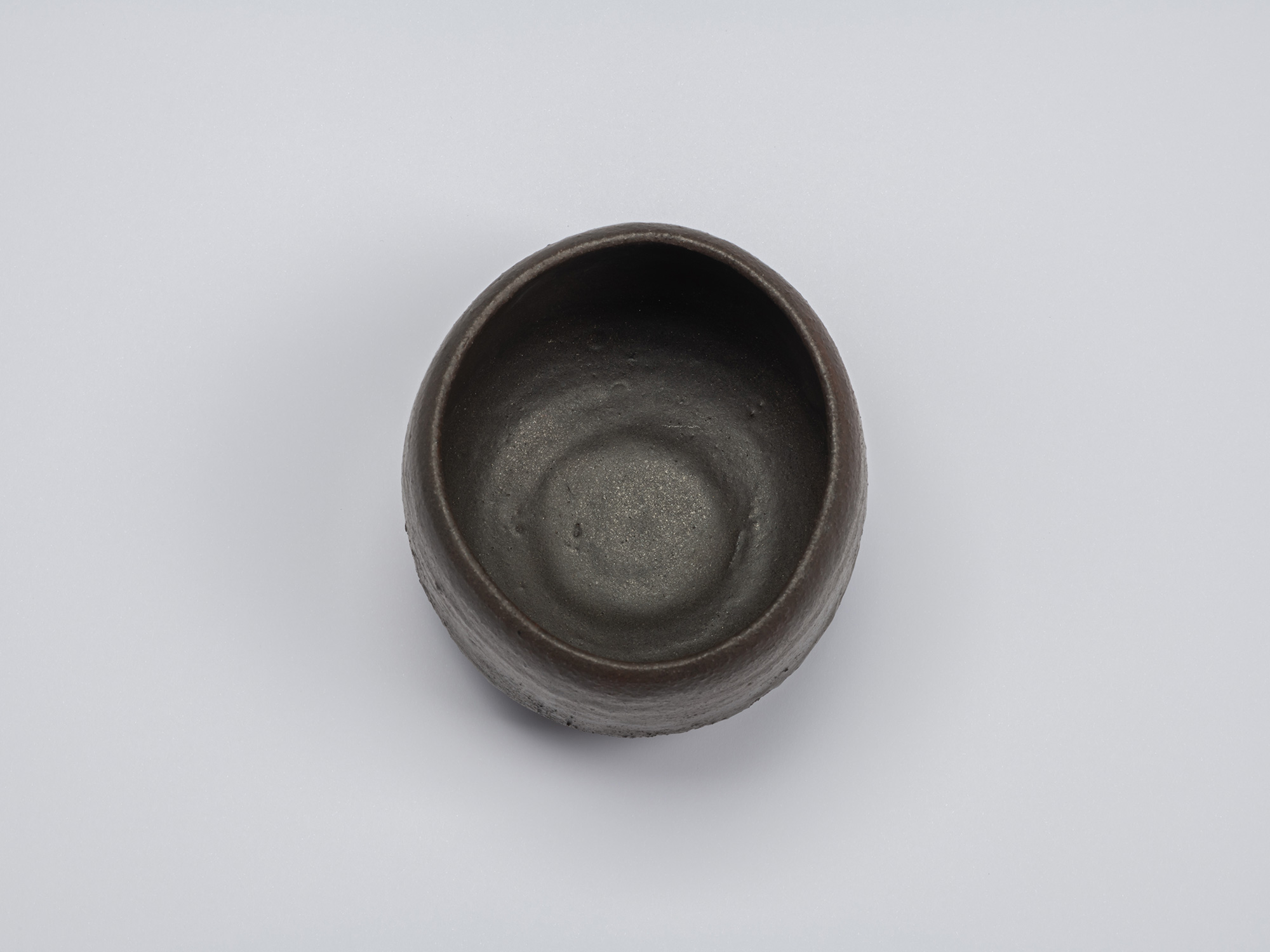 Overhead view of the black tea bowl showing a deep rounded interior with a matte dark surface and...