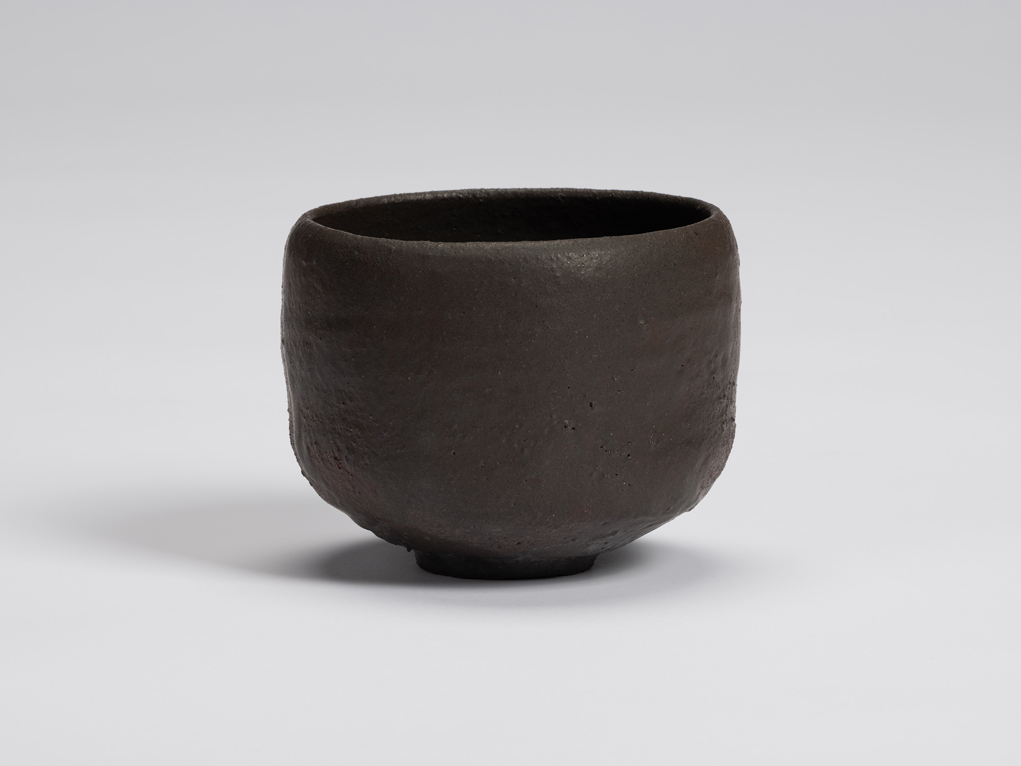 Hand-formed black tea bowl by Shiro Tsujimura with a rounded cylindrical form, gently curved sides,...