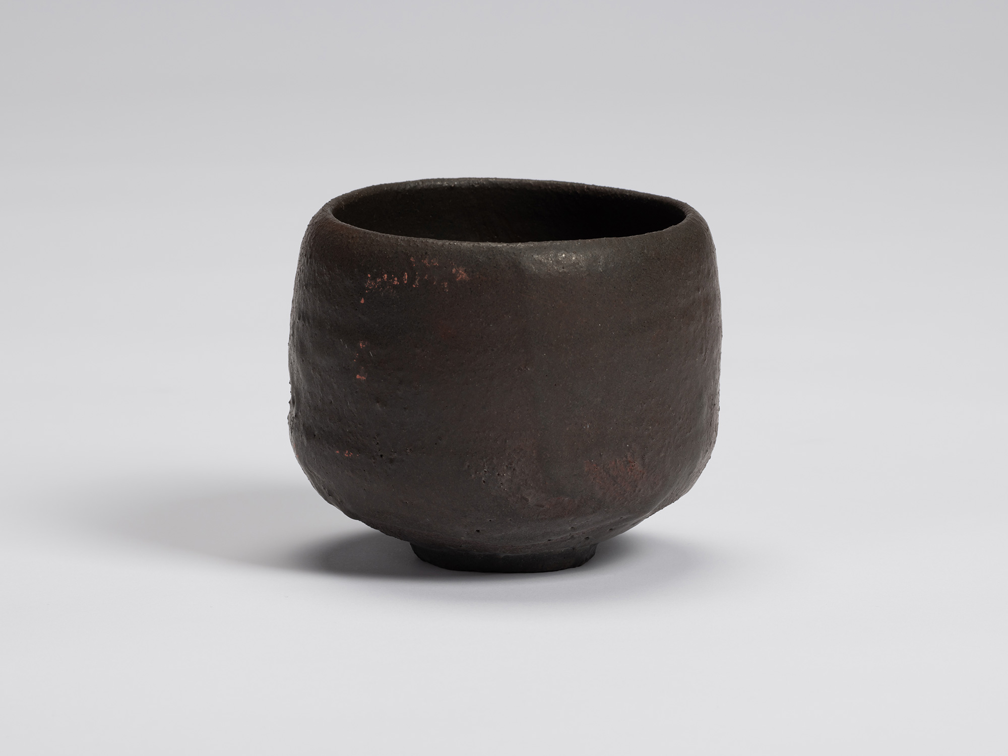 Hand-formed black tea bowl by Shiro Tsujimura with a rounded cylindrical form, gently curved sides,...