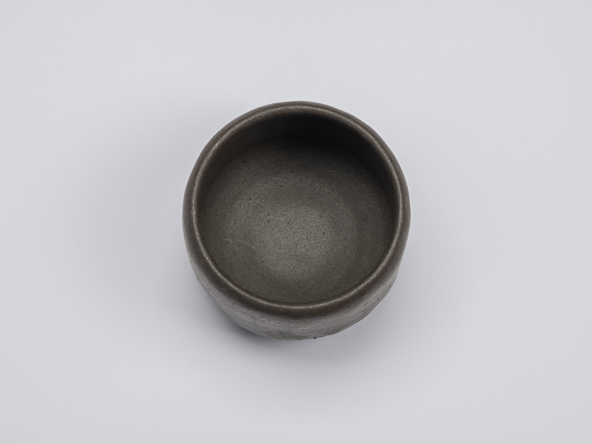 Overhead view of Kuro Chawan revealing a smooth, deep interior with a finely textured charcoal-gray...