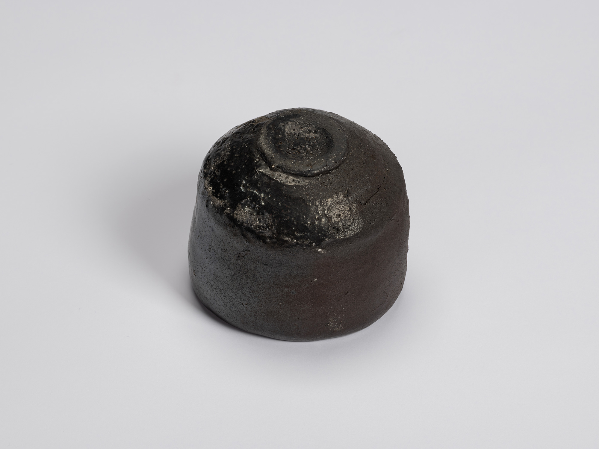 Bottom view of Shiro Tsujimura's Kuro Chawan showing the neatly trimmed circular foot ring surrounded...
