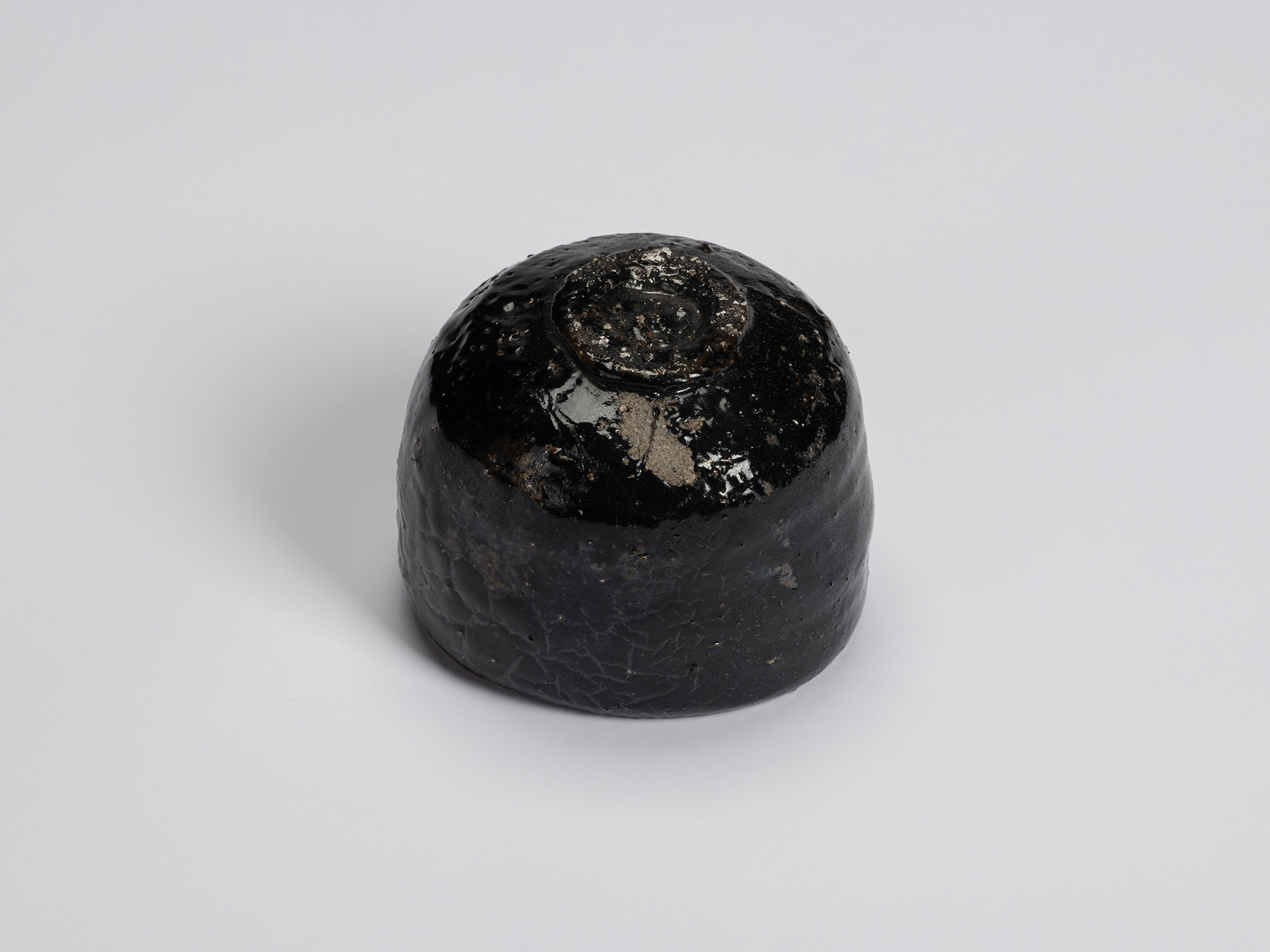 Bottom view of Kuro Chawan by Shiro Tsujimura, revealing its trimmed circular foot ring, glossy...