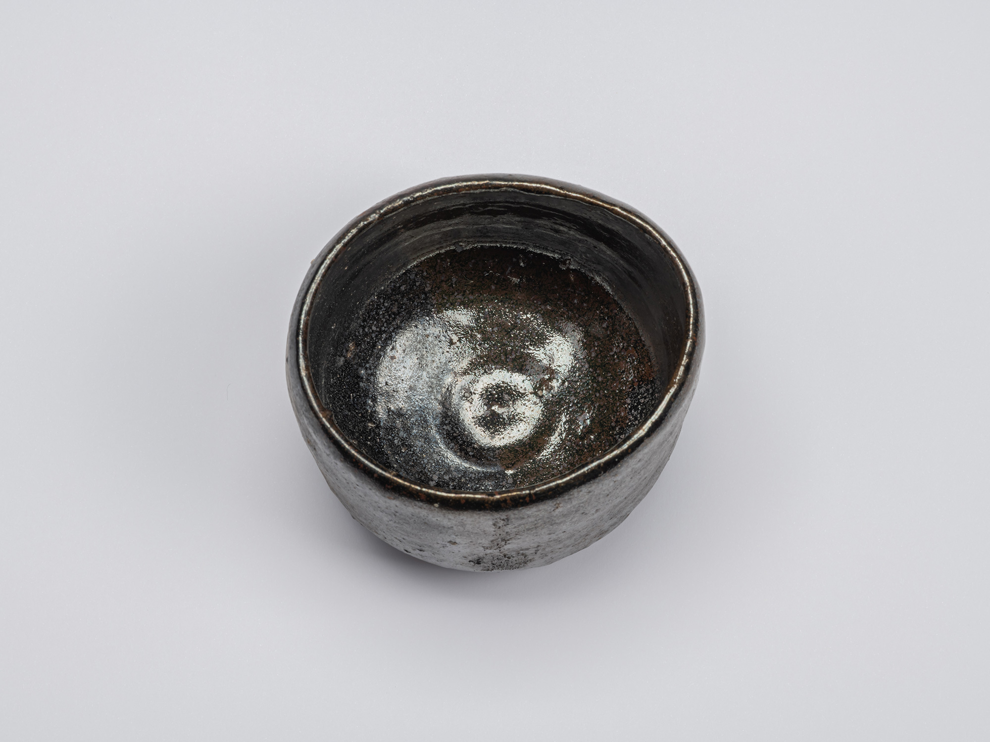 Overhead view of the Kuro Chawan revealing a glossy black interior with concentric throwing marks,...