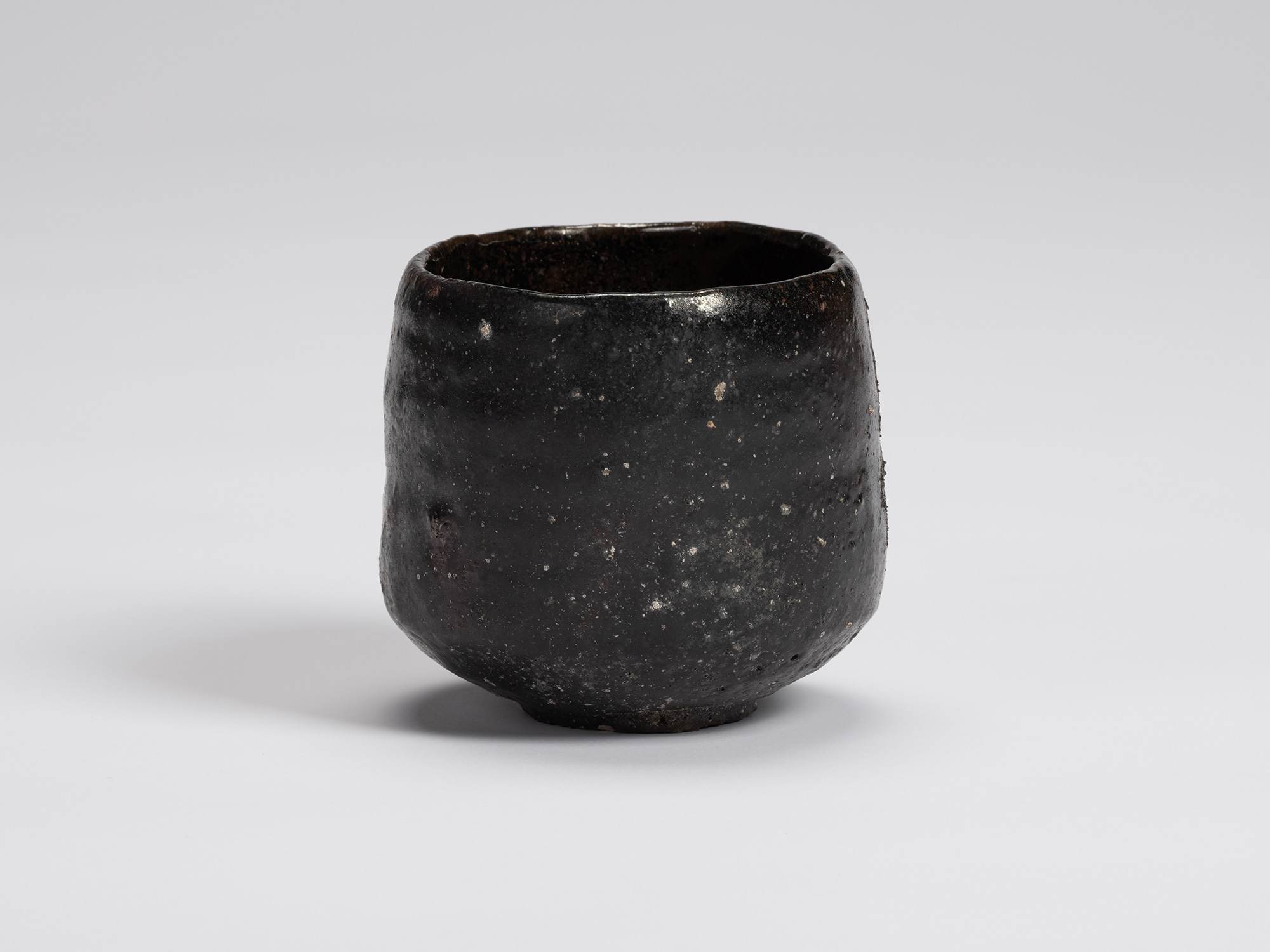 Front view of a hand-formed Kuro Chawan by Shiro Tsujimura featuring a rounded cylindrical form...