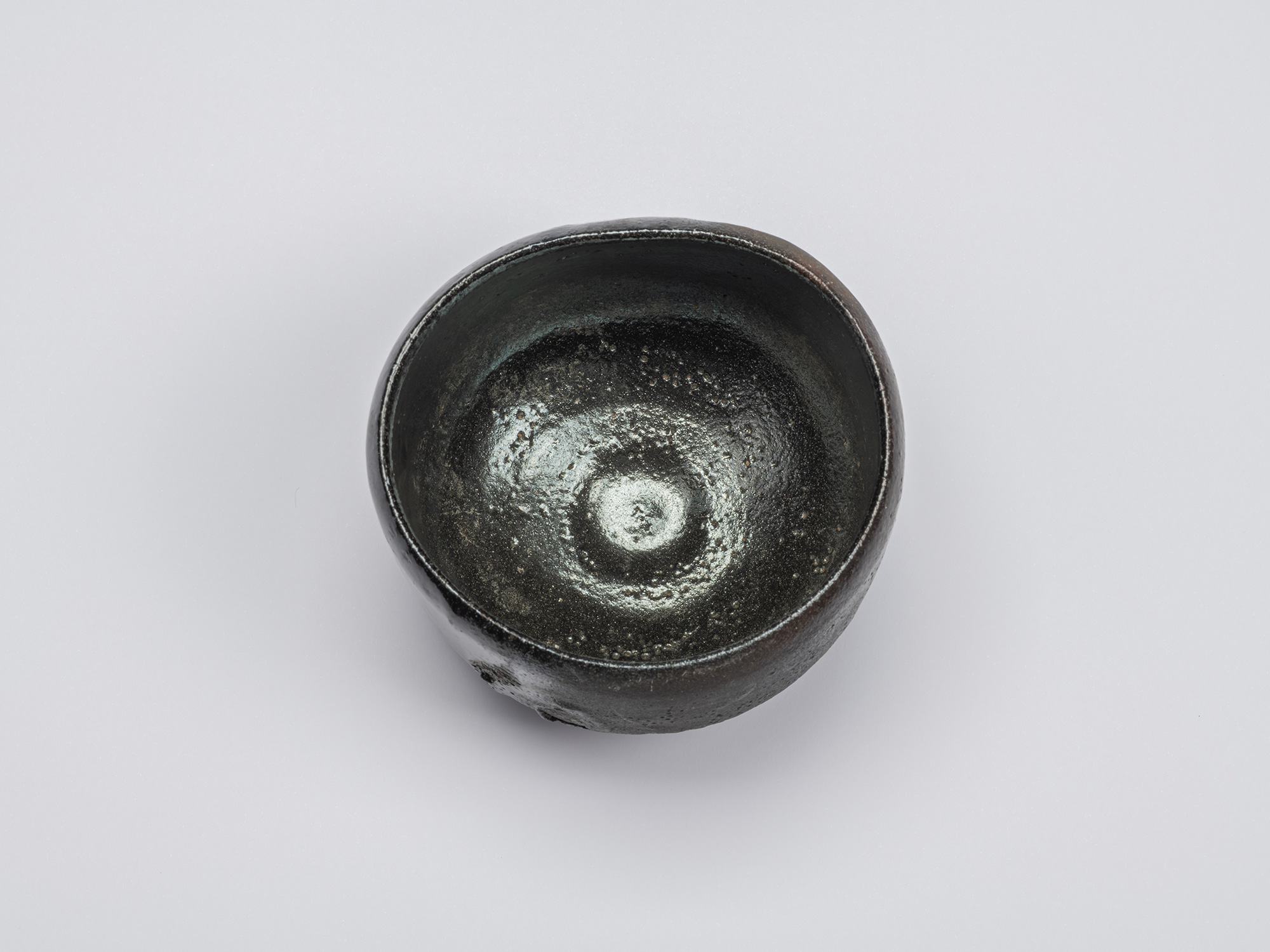 Overhead view of the Kuro Chawan showing a glossy black glazed interior with concentric throwing...