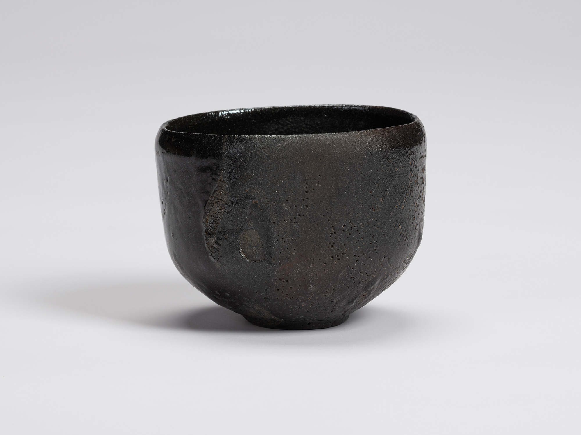 Front view of Shiro Tsujimura's Kuro Chawan featuring a rounded, slightly tapering form with a...