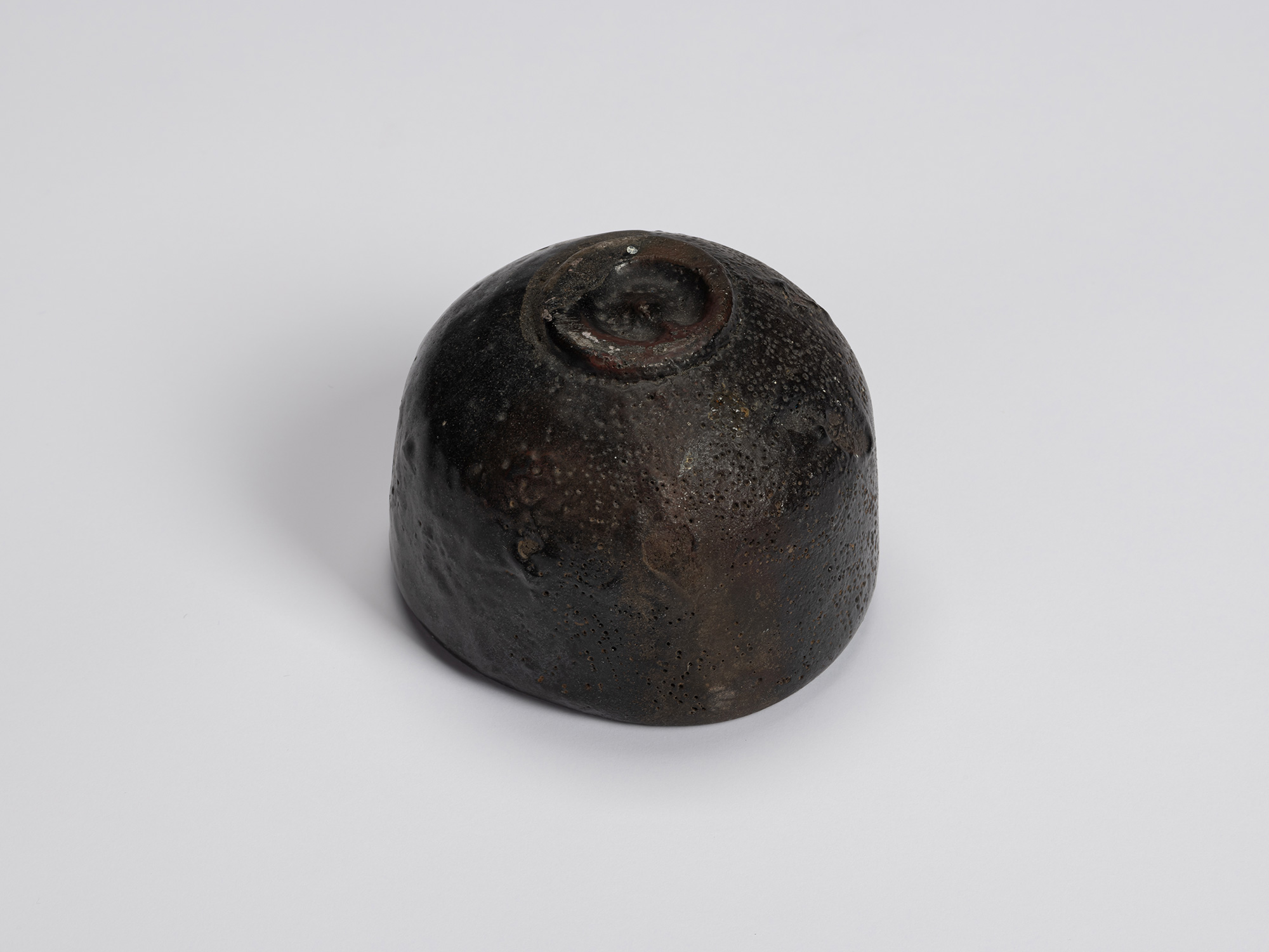 Bottom view of Shiro Tsujimura's Kuro Chawan showing the rounded exterior, small recessed foot...