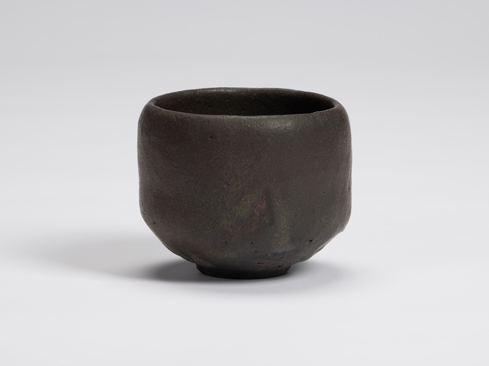 Hand-formed black tea bowl by Shiro Tsujimura with a rounded cylindrical form, gently tapered base,...