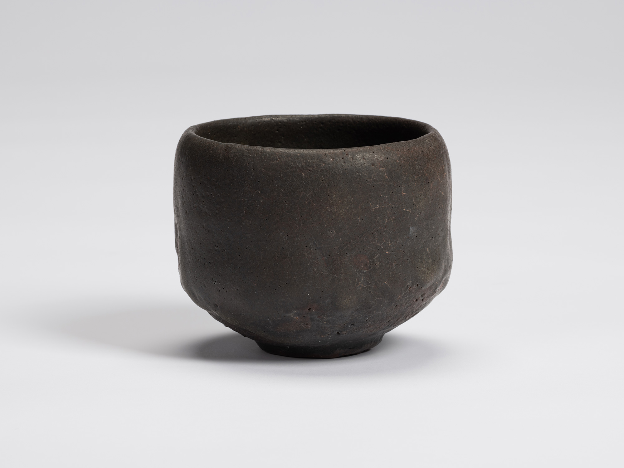 Hand-formed black tea bowl by Shiro Tsujimura with a rounded cylindrical form, gently tapered base,...