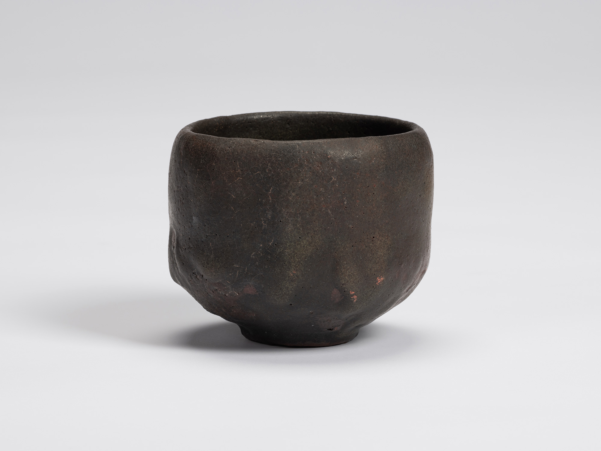 Hand-formed black tea bowl by Shiro Tsujimura with a rounded cylindrical form, gently tapered base,...
