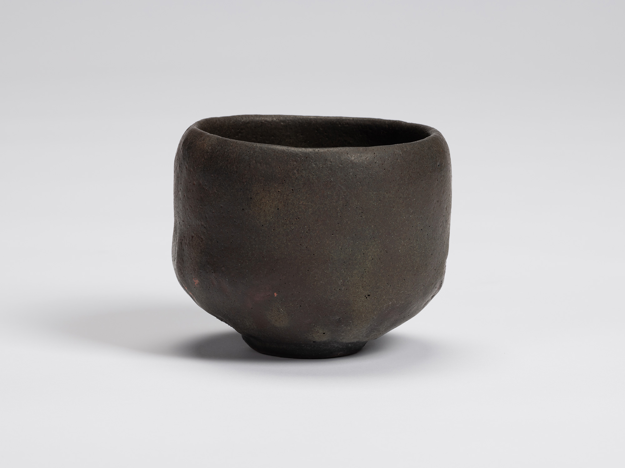 Hand-formed black tea bowl by Shiro Tsujimura with a rounded cylindrical form, gently tapered base,...