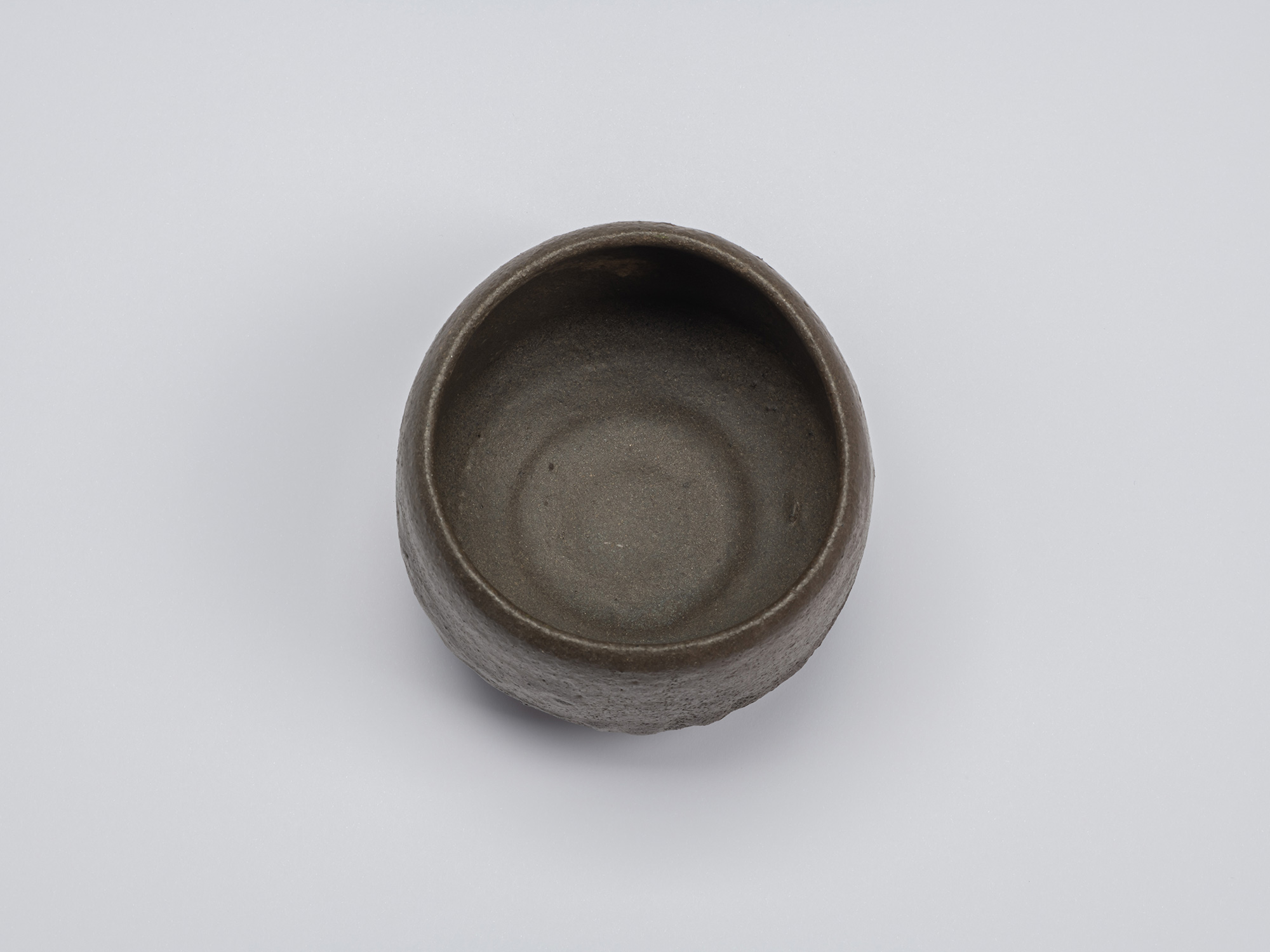 Overhead view of the black tea bowl showing a deep rounded interior with a matte gray-brown surface...