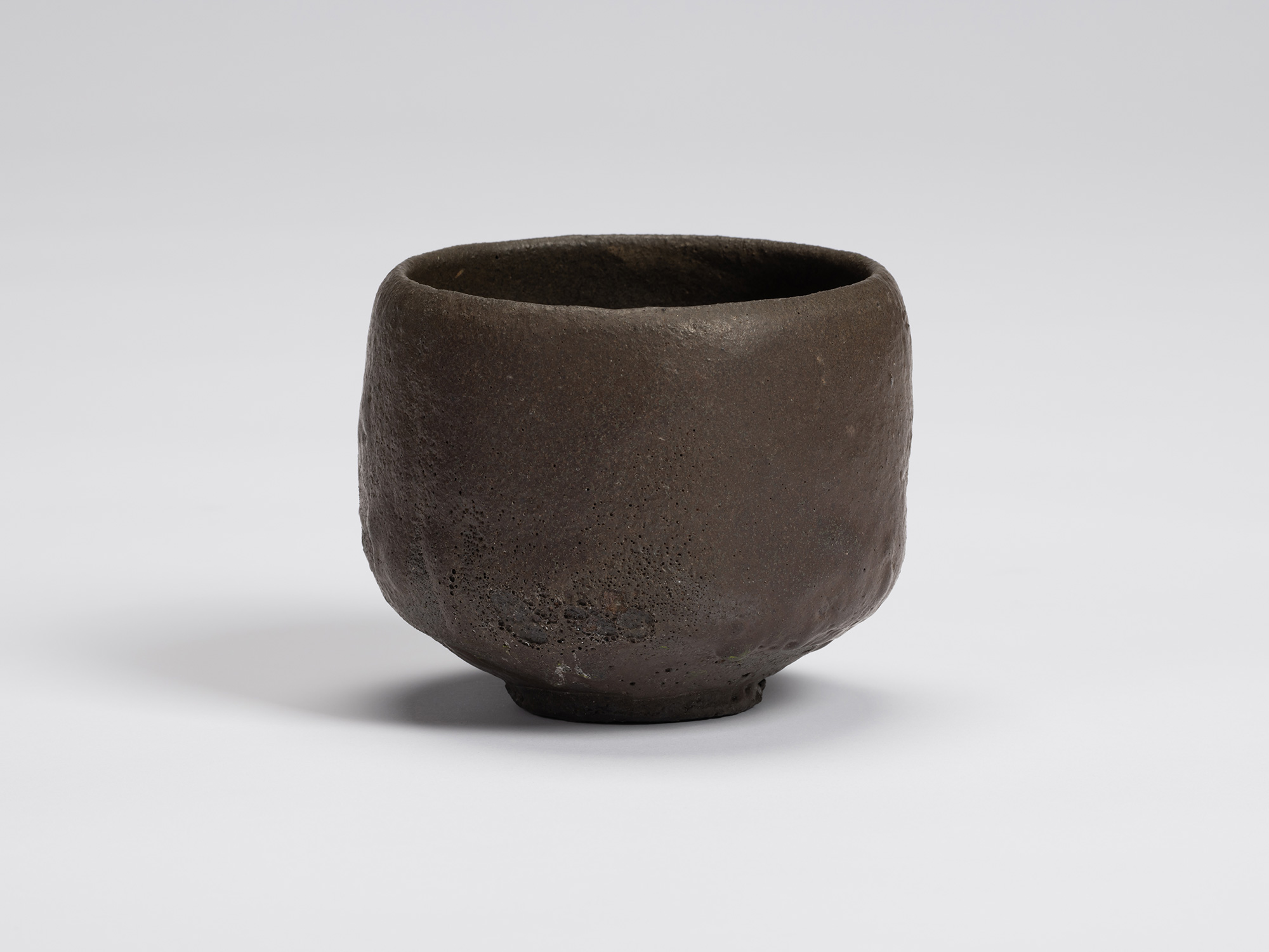 Hand-formed black tea bowl by Shiro Tsujimura with a rounded cylindrical form, gently tapered base,...