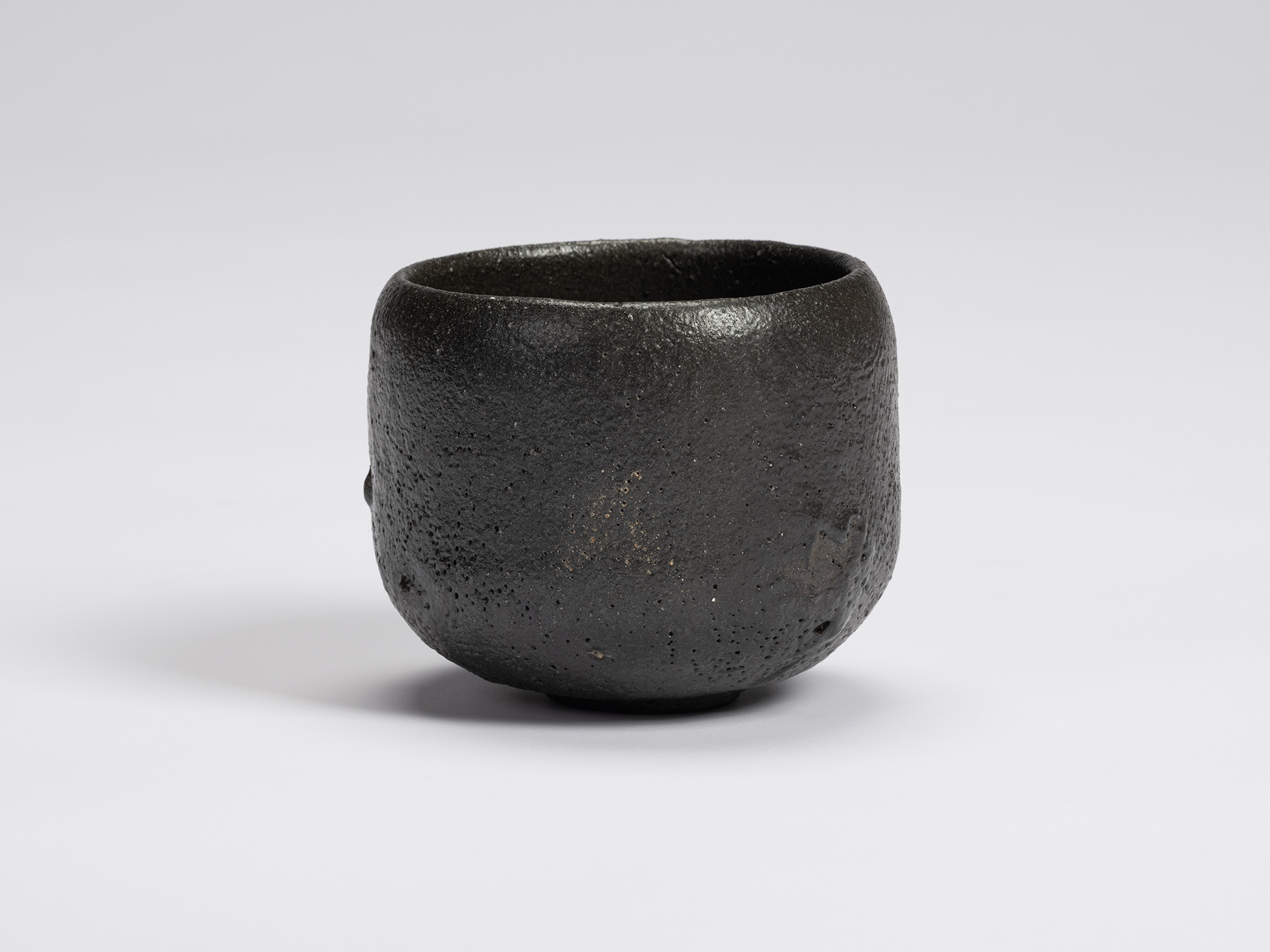 Front view of Chawan No. 7 by Shiro Tsujimura, a hand-formed black tea bowl with a rounded cylindrical...