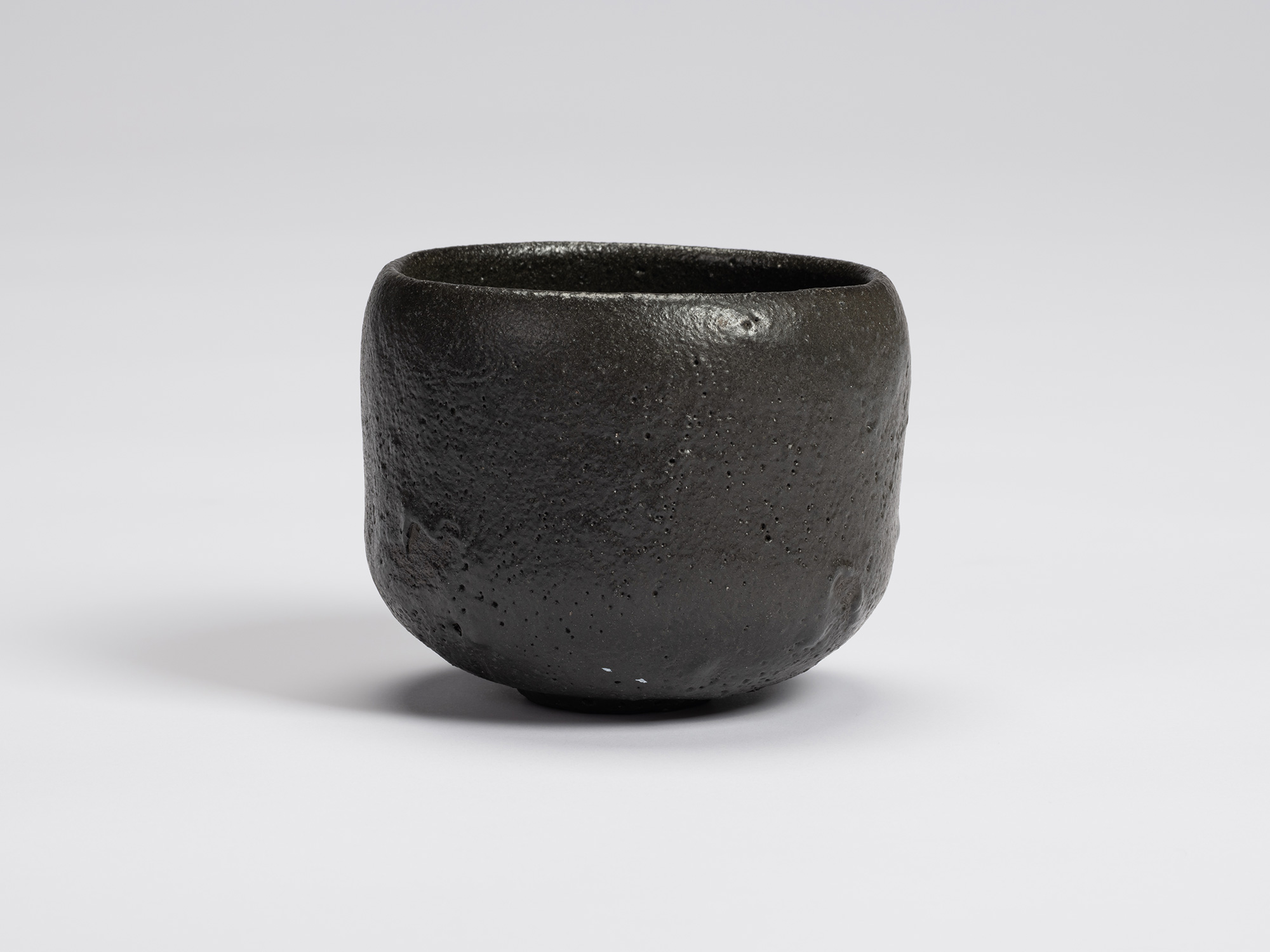 Front view of Chawan No. 7 by Shiro Tsujimura, a hand-formed black tea bowl with a rounded cylindrical...