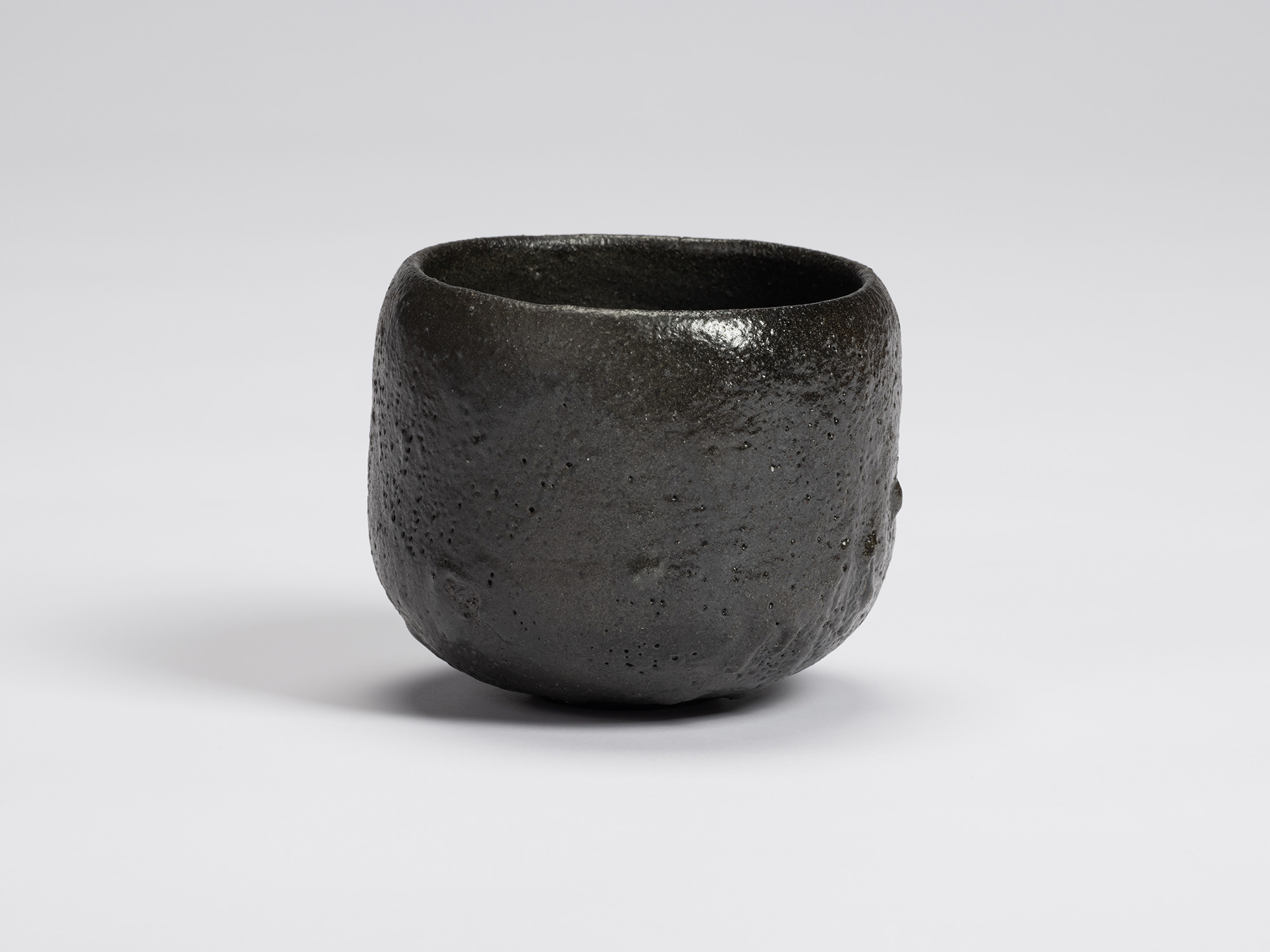 Front view of Chawan No. 7 by Shiro Tsujimura, a hand-formed black tea bowl with a rounded cylindrical...