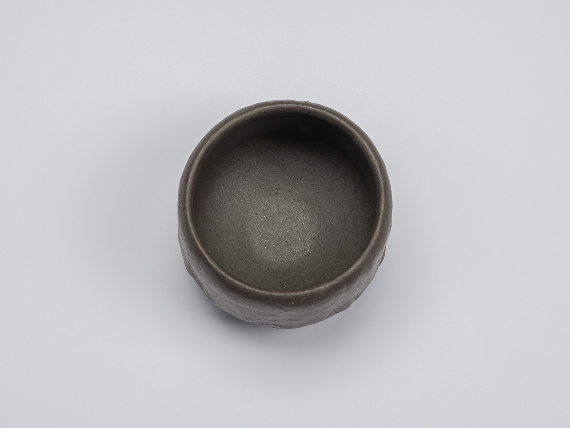 Overhead view of Shiro Tsujimura's black tea bowl showing the softly rounded rim and smooth, deep...