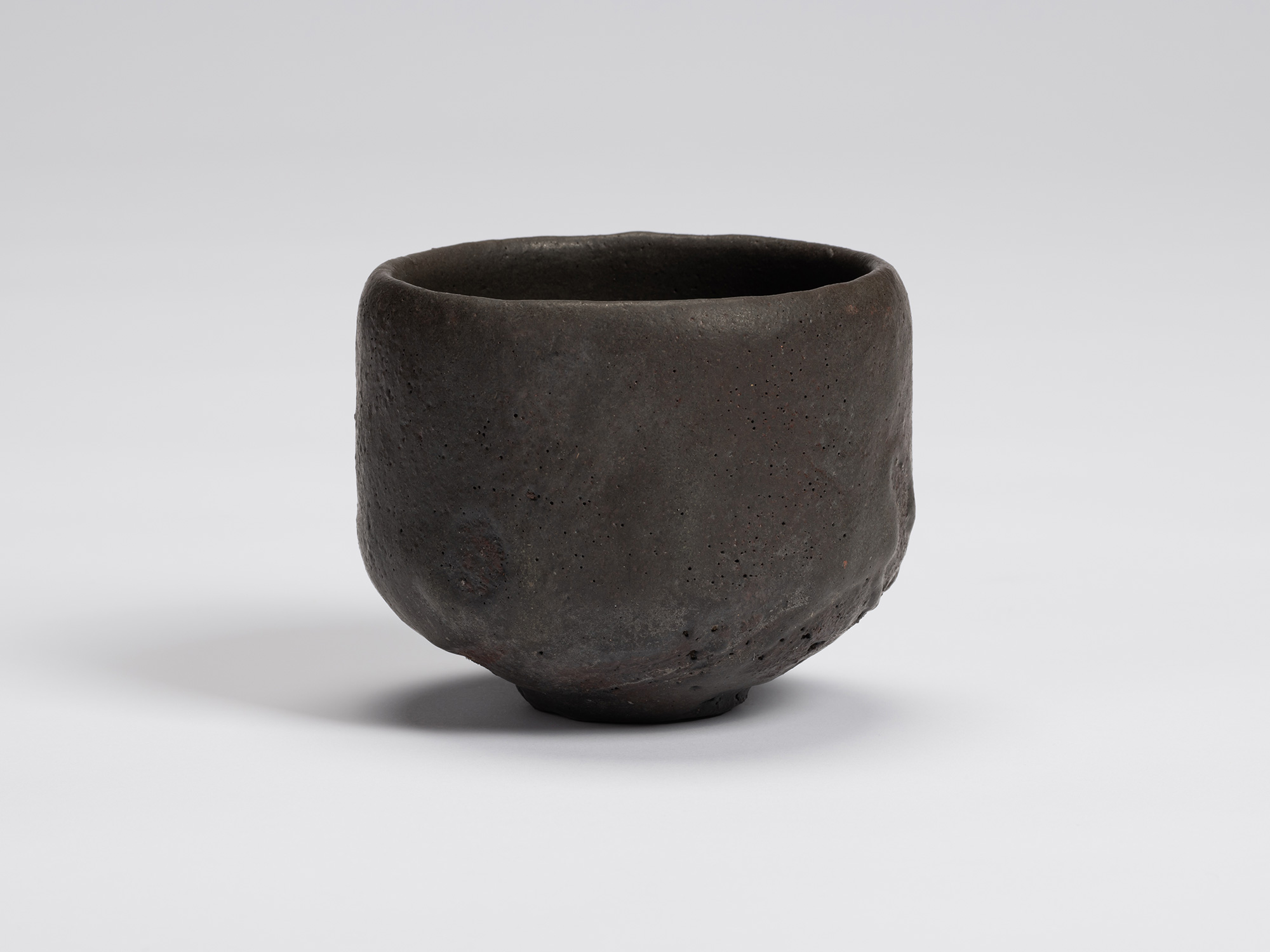 Front view of Shiro Tsujimura's hand-formed black tea bowl with a rounded cylindrical form, matte...