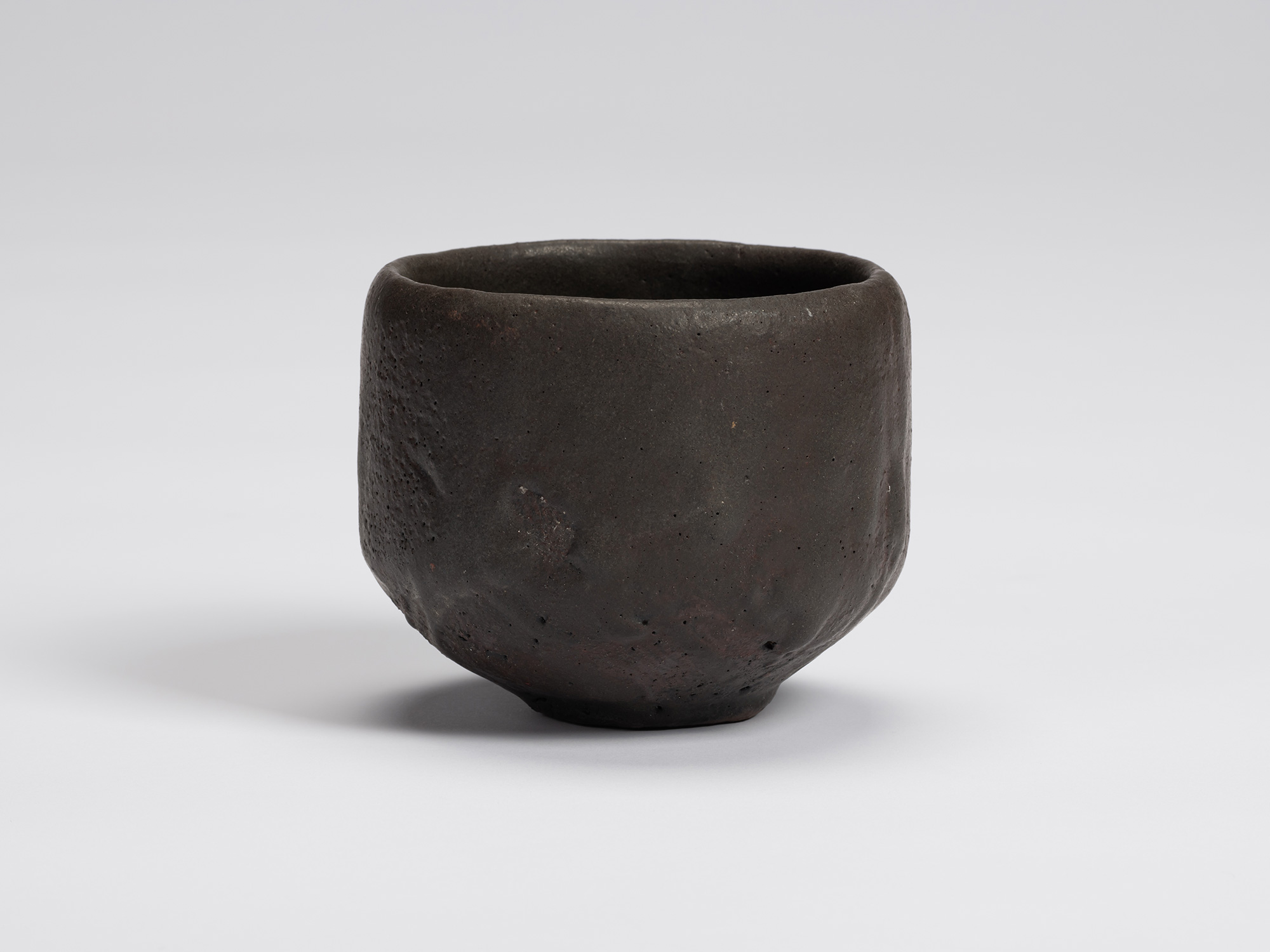 Front view of Shiro Tsujimura's hand-formed black tea bowl with a rounded cylindrical form, matte...