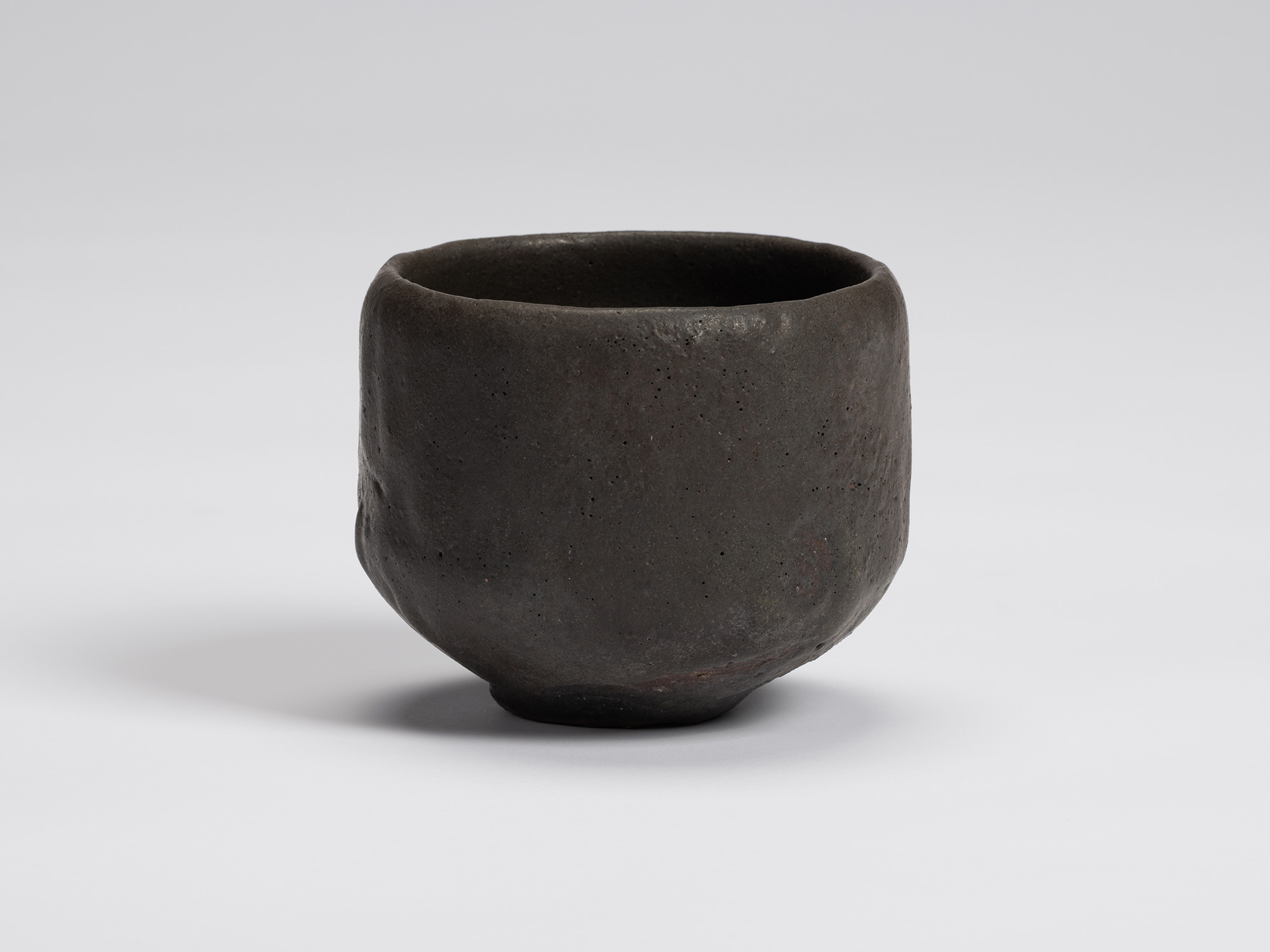 Front view of Shiro Tsujimura's hand-formed black tea bowl with a rounded cylindrical form, matte...