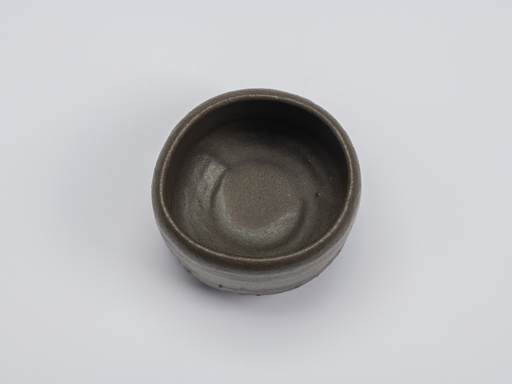 Overhead view of Chawan No. 9 by Shiro Tsujimura, revealing a smooth charcoal-gray interior with...