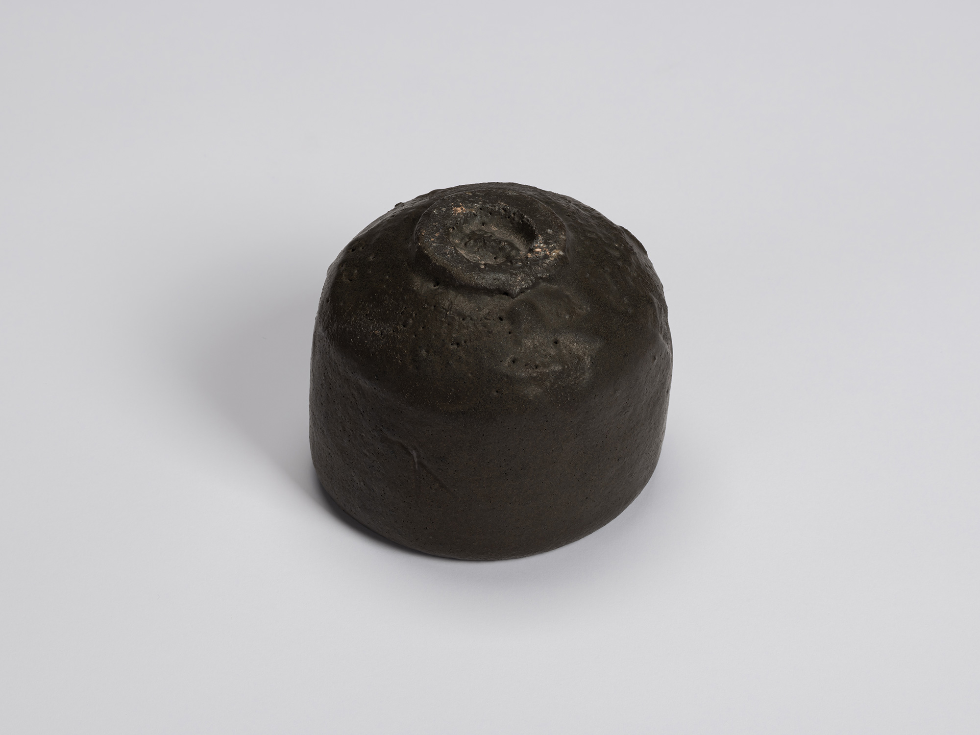 Bottom view of Chawan No. 9 showing the rounded foot with a small trimmed foot ring. The dark charcoal...