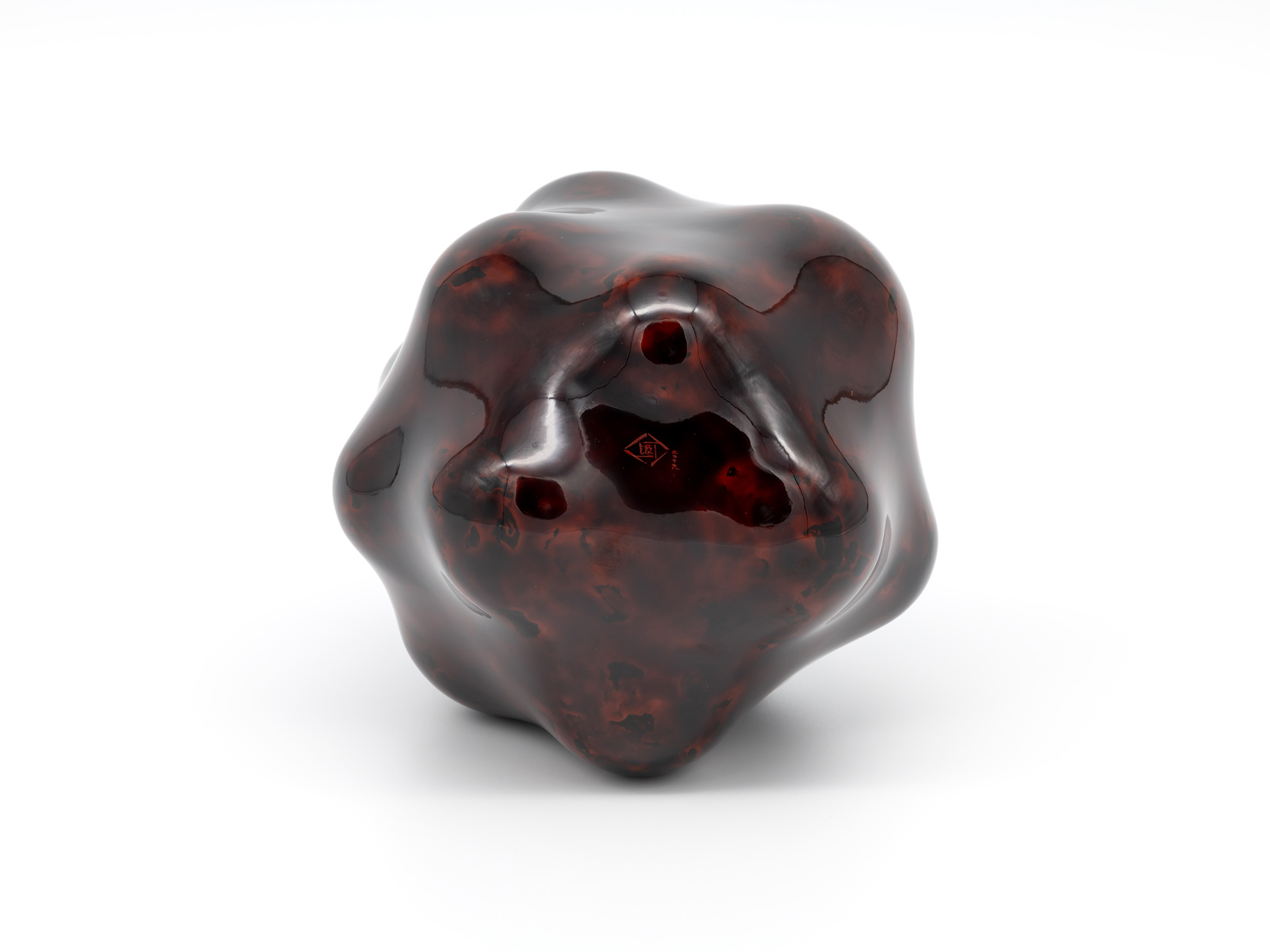 Bottom view of Untitled by Genta Ishizuka showing the polished foot of the dark lacquer sculpture....