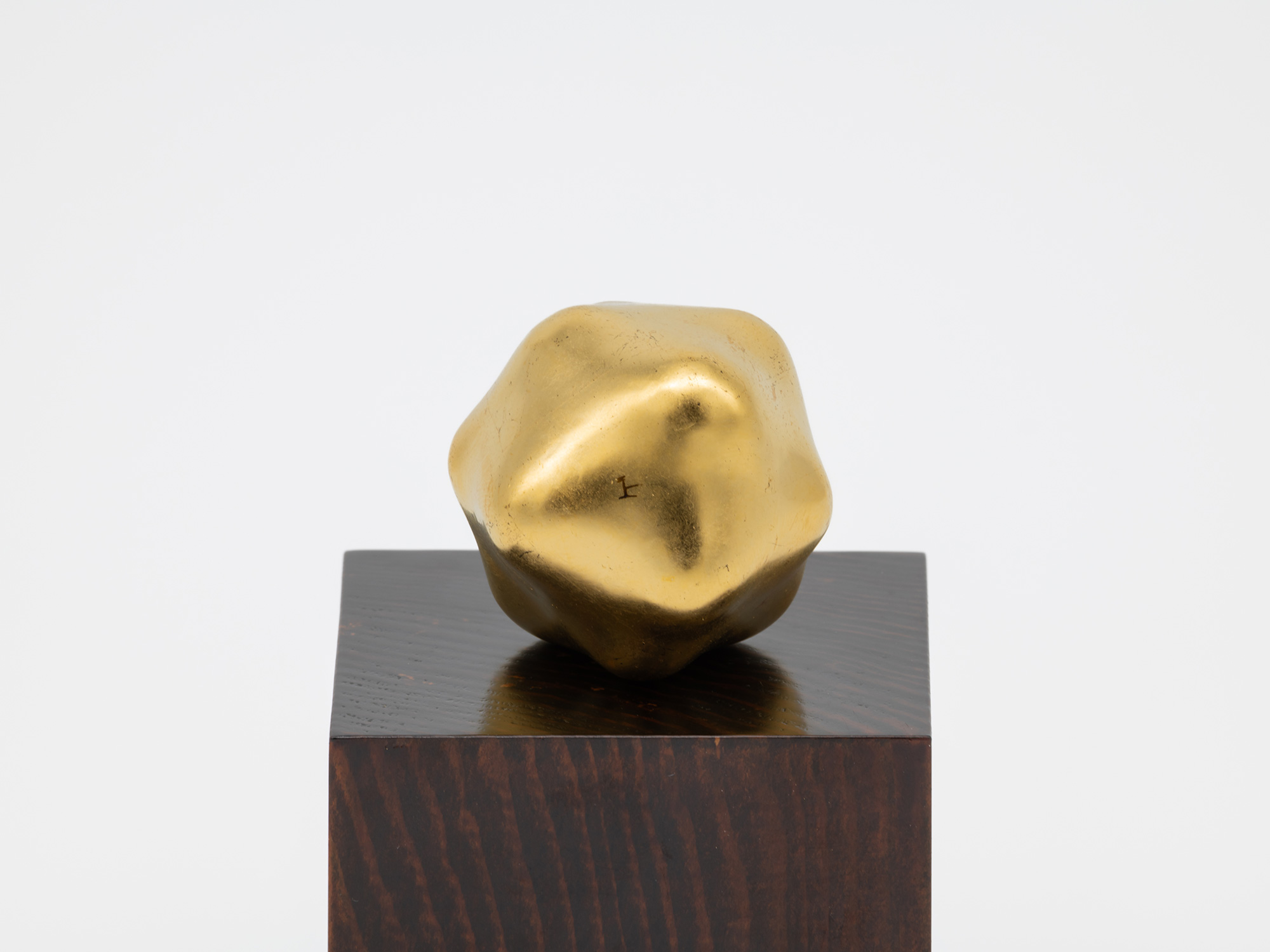 The foot of Untitled by Genta Ishizuka showing the artist's mark. It is resting on its accompanying...