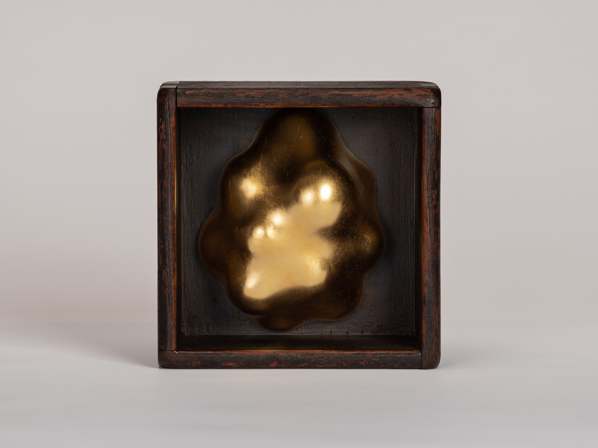 Front view of Untitled (Hung in a Box) #1 by Genta Ishizuka. An organic gold leaf lacquer form...