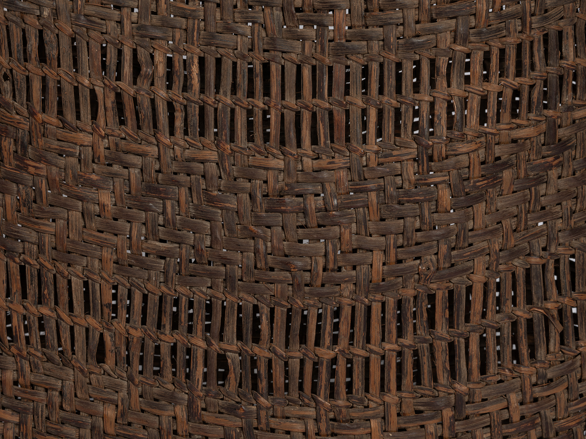 Close-up of a basket woven from wild mountain grape bark, showing alternating bands of dense basket...
