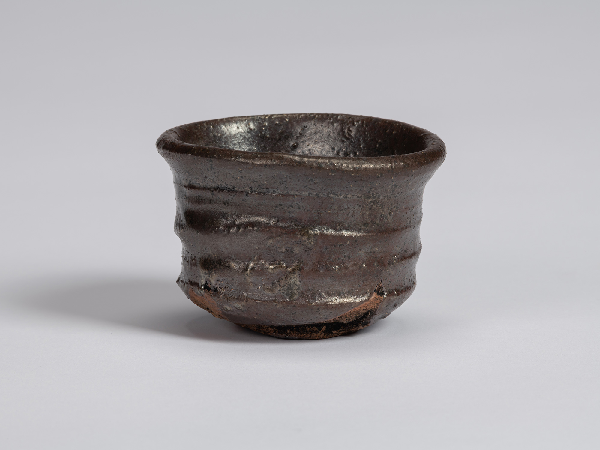View of a Kuro Guinomi by Shiro Tsujimura, with a cylindrical form, slightly flared rim, and dark...